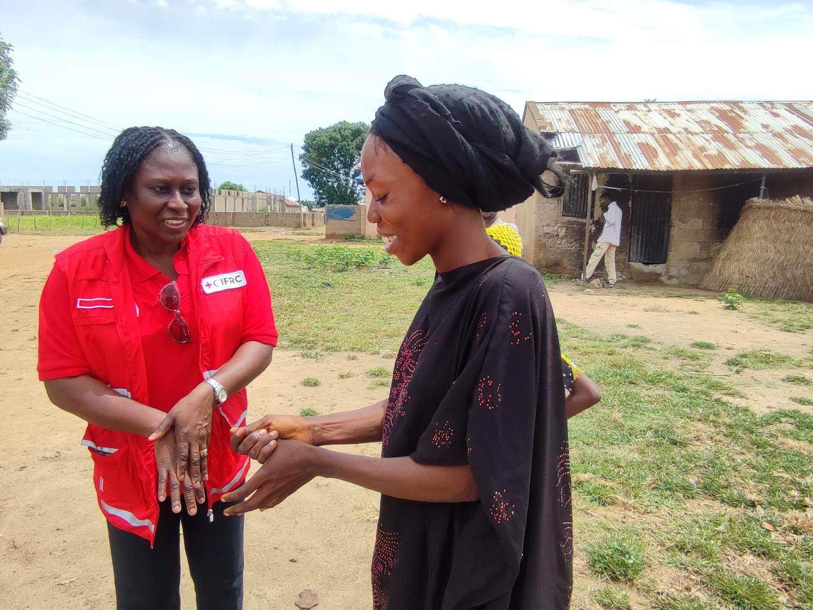 An IFRC Program Officer for the Reach Initiative, Lilian Adeogba, guides a community health worker in the essential practice of handwashing, ensuring health and safety for all.