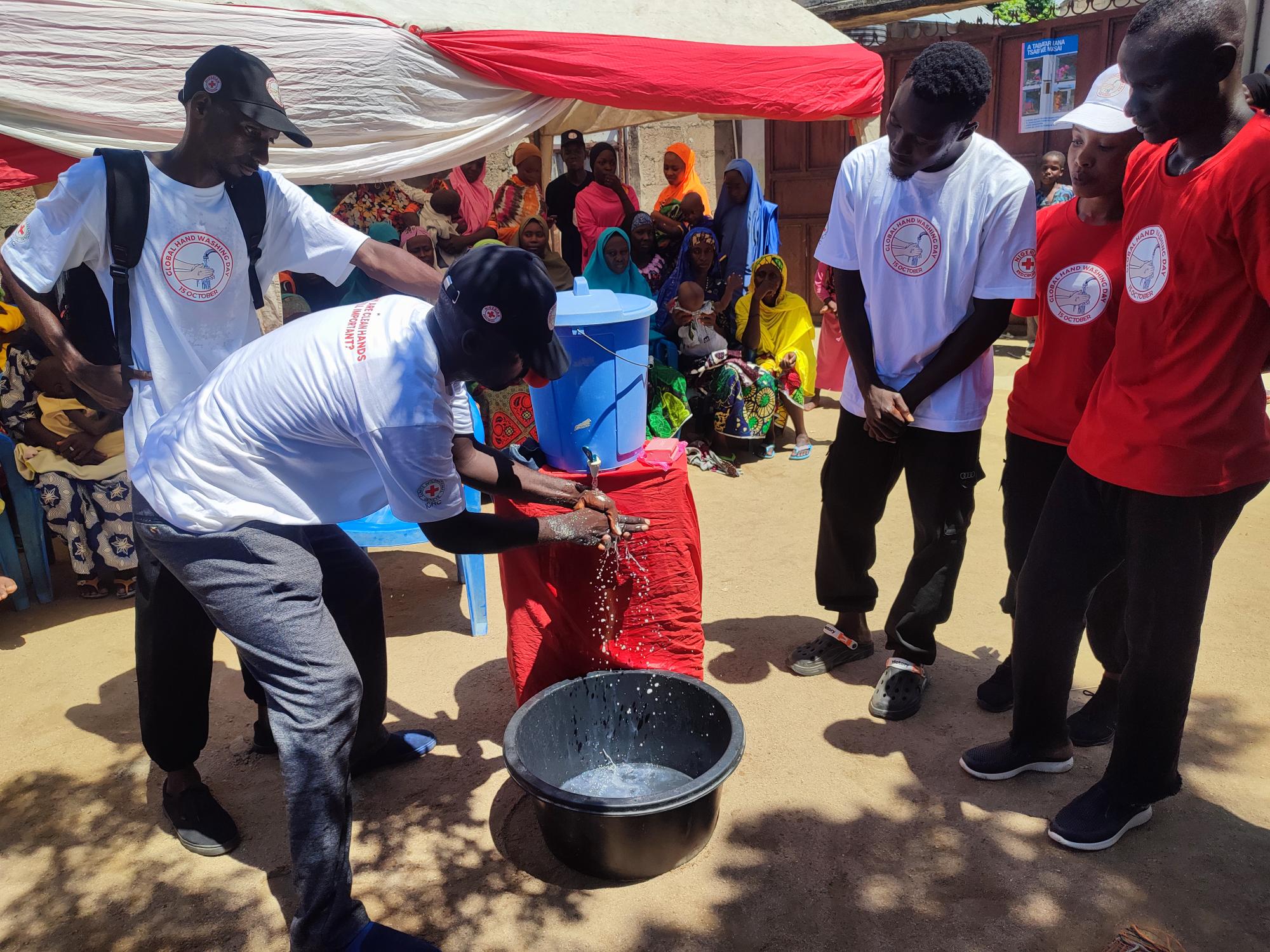 Nigerian Red Cross Society volunteers training people in the Fufore community in Adamawa state, Nigeria, on the life-saving practice of handwashing.