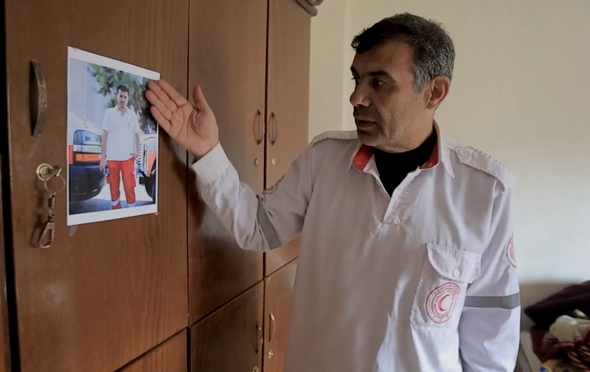 Palestine Red Crescent paramedic Jihad Mansour looks at a picture of his friend and colleague Fadi Al-Maani, a fellow paramedic who died in the line of duty in 2024.