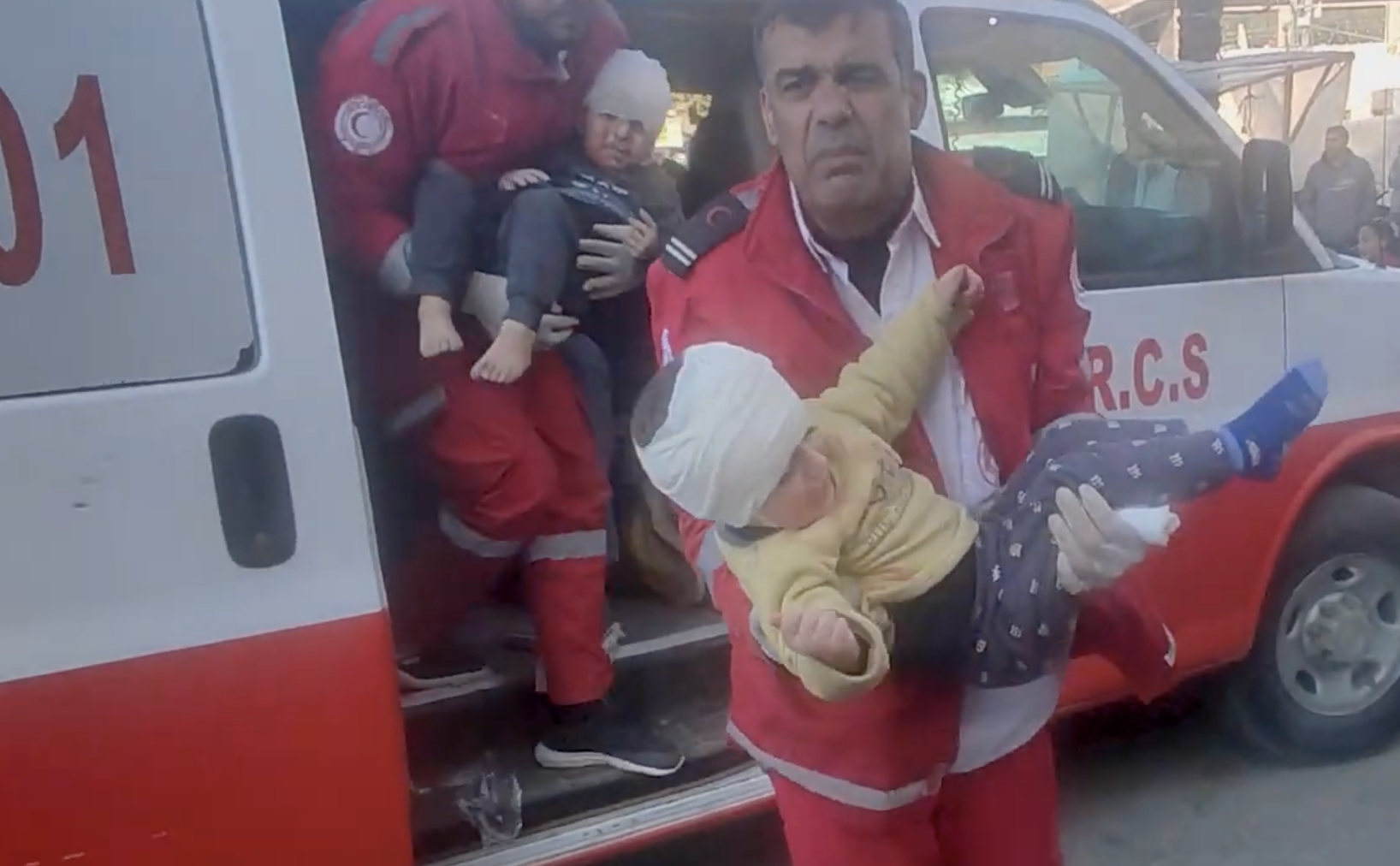 Palestine Red Crescent volunteer Jihad Mansour carries and injured child from an ambulance into the hospital.