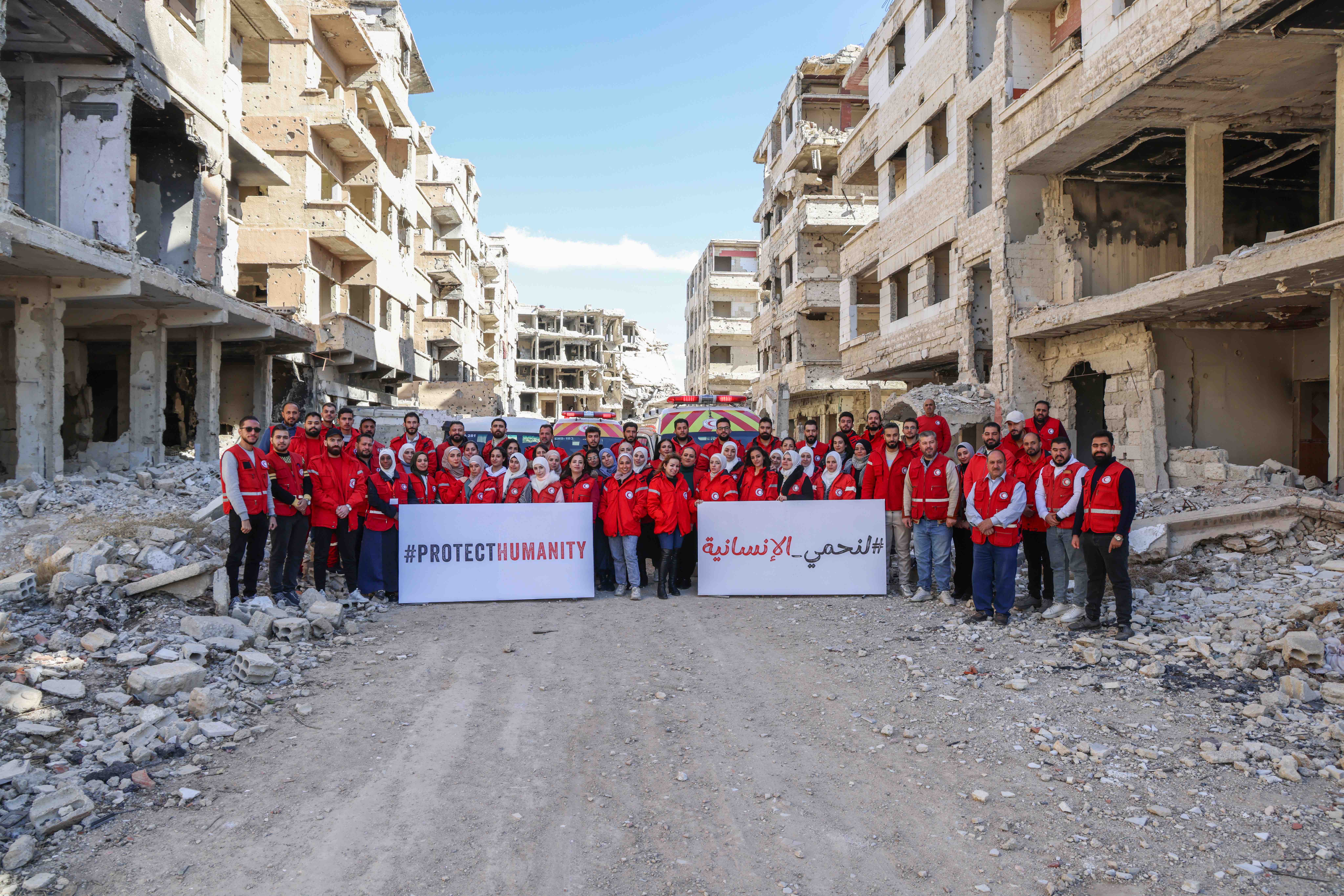 Members of the Syrian Arab Red Crescent gathered among buildings destroyed during the country’s internal conflict.