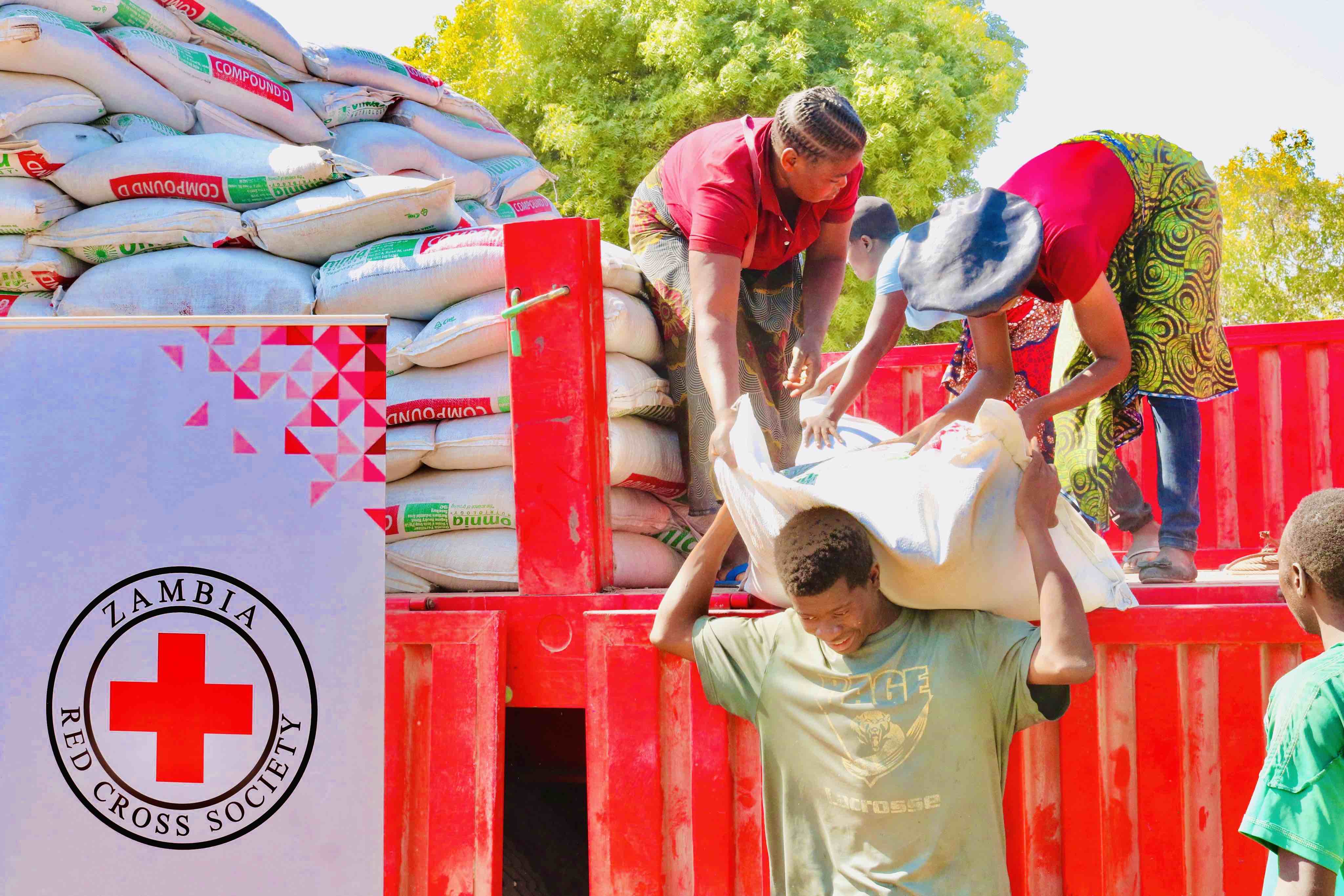 Volunteers from the Zambia Red Cross Sosciety unload bags of seeds, fertilizers and other supports to farmers for their winter crops.