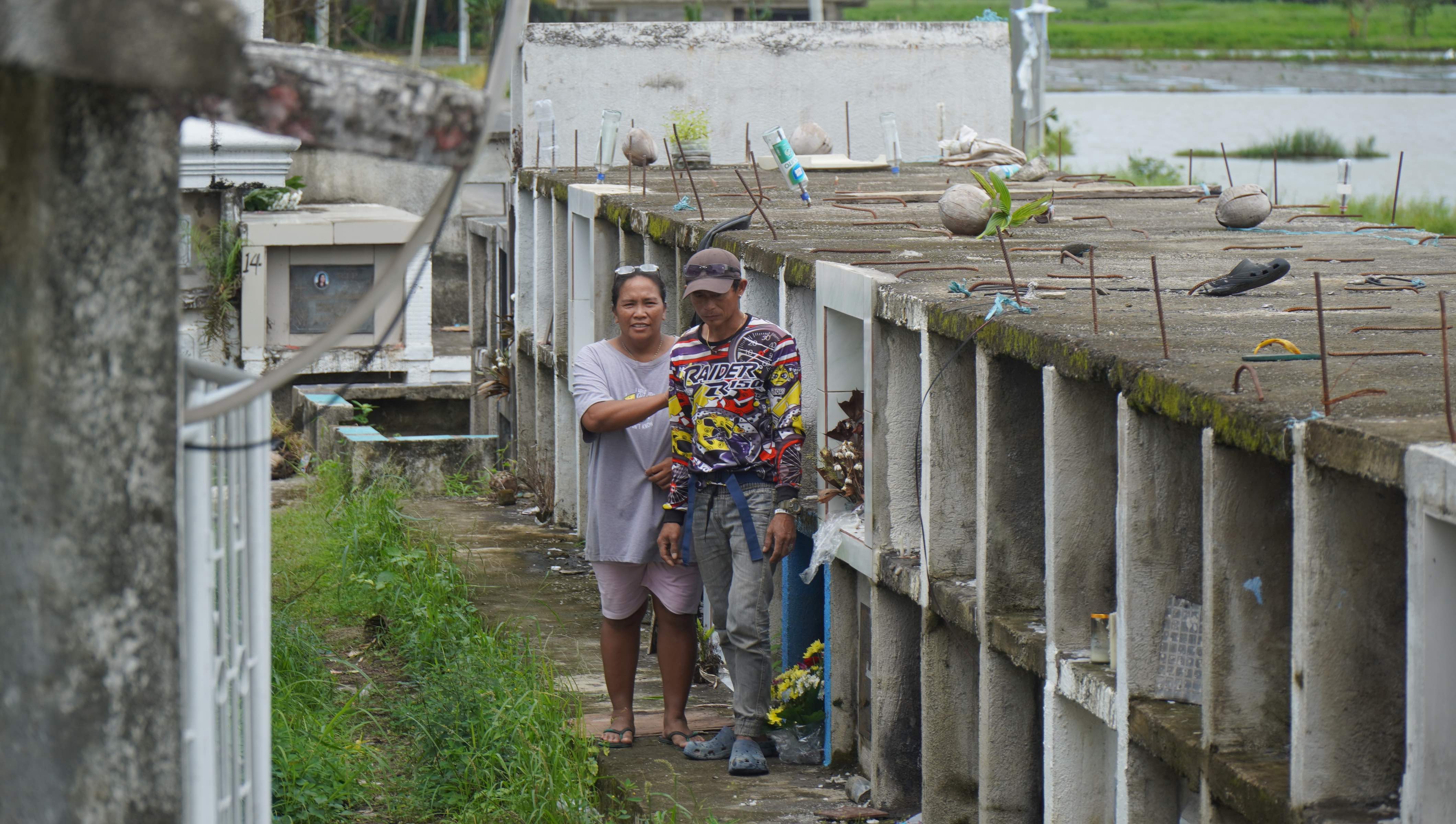 Janet Menes and her husband Albiz Menes walk through the cemetery where they took shelter during severe storms in November 2024.