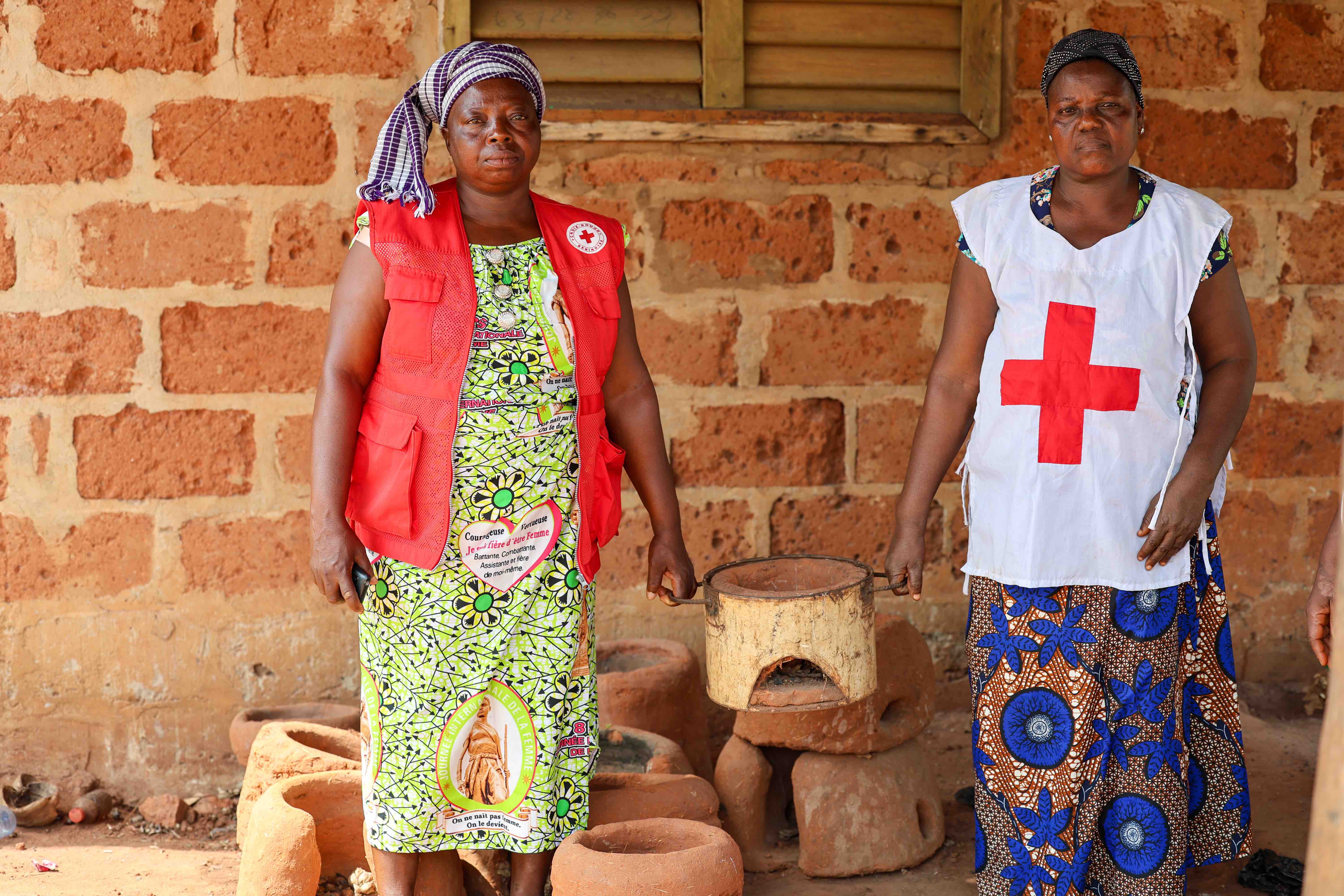 Members of Mothers’ Club in Benin hold one of the fuel-efficient stoves they made by hand using locally available clay.