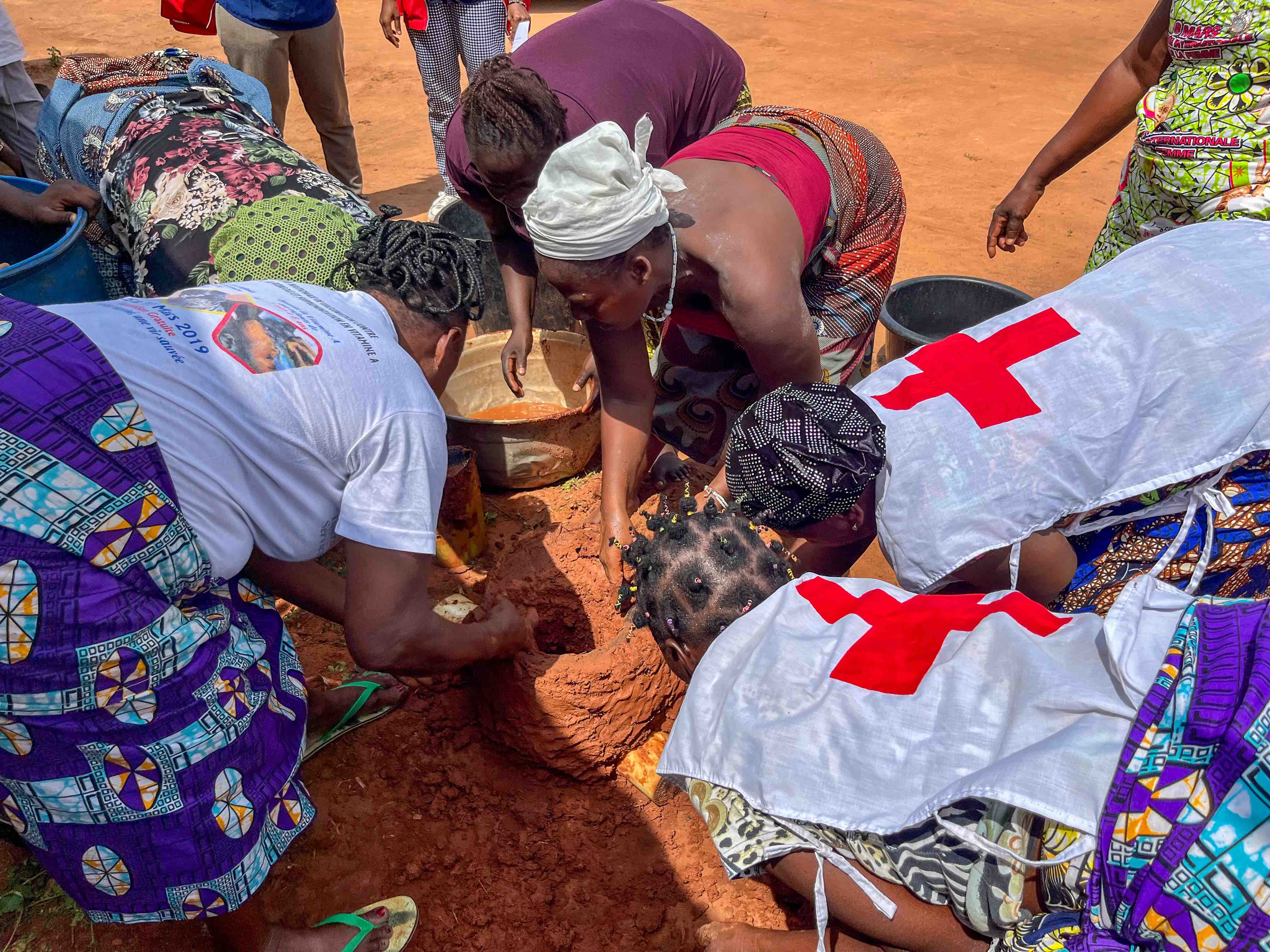 Members of Mothers’Club in Benin work together to building a fuel-efficient stove using locally available clay.