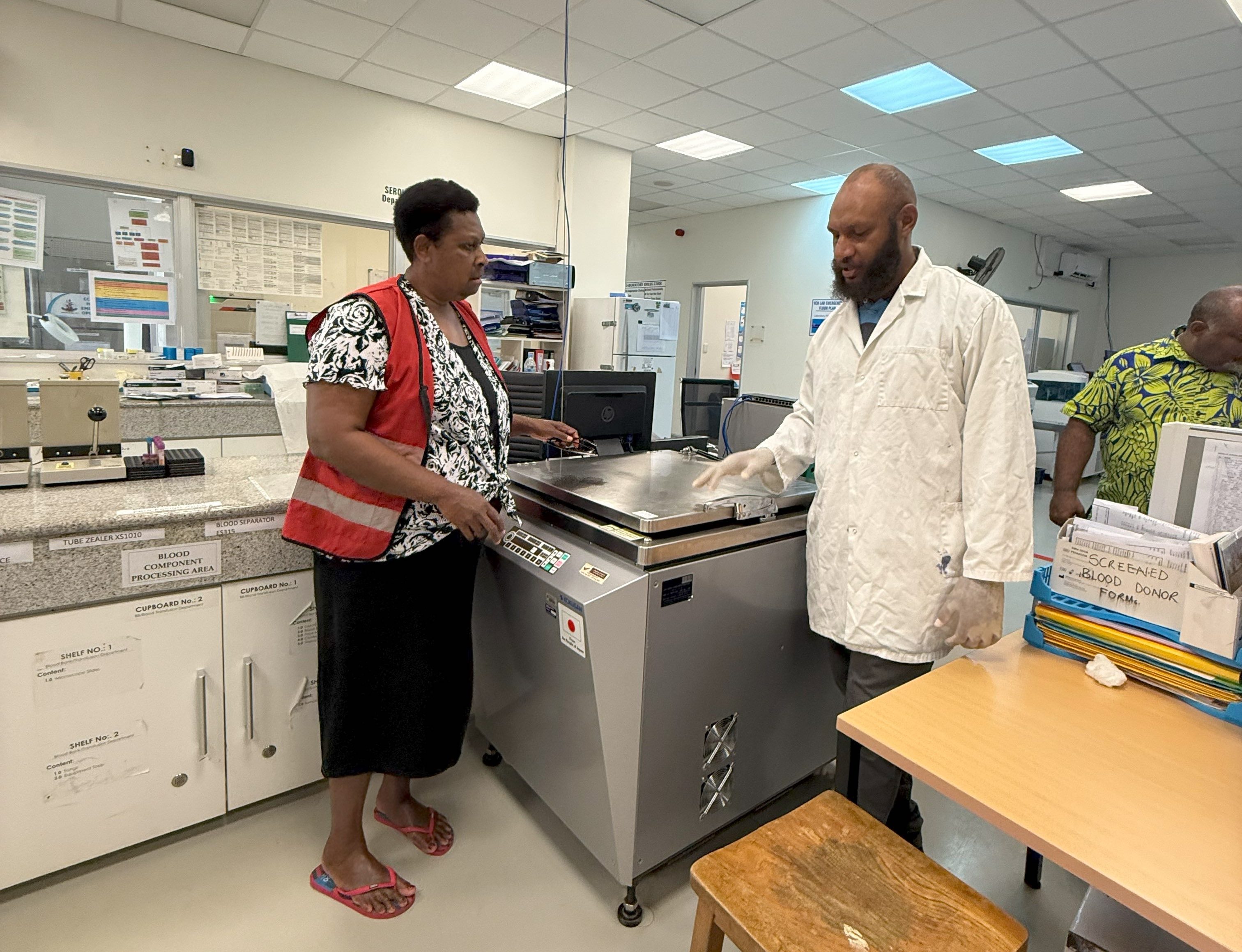 Representatives for the Vanuatu Red Cross and Port Vila hospital stand next to new blood processing equipment provided by the Australian Red Cross. 