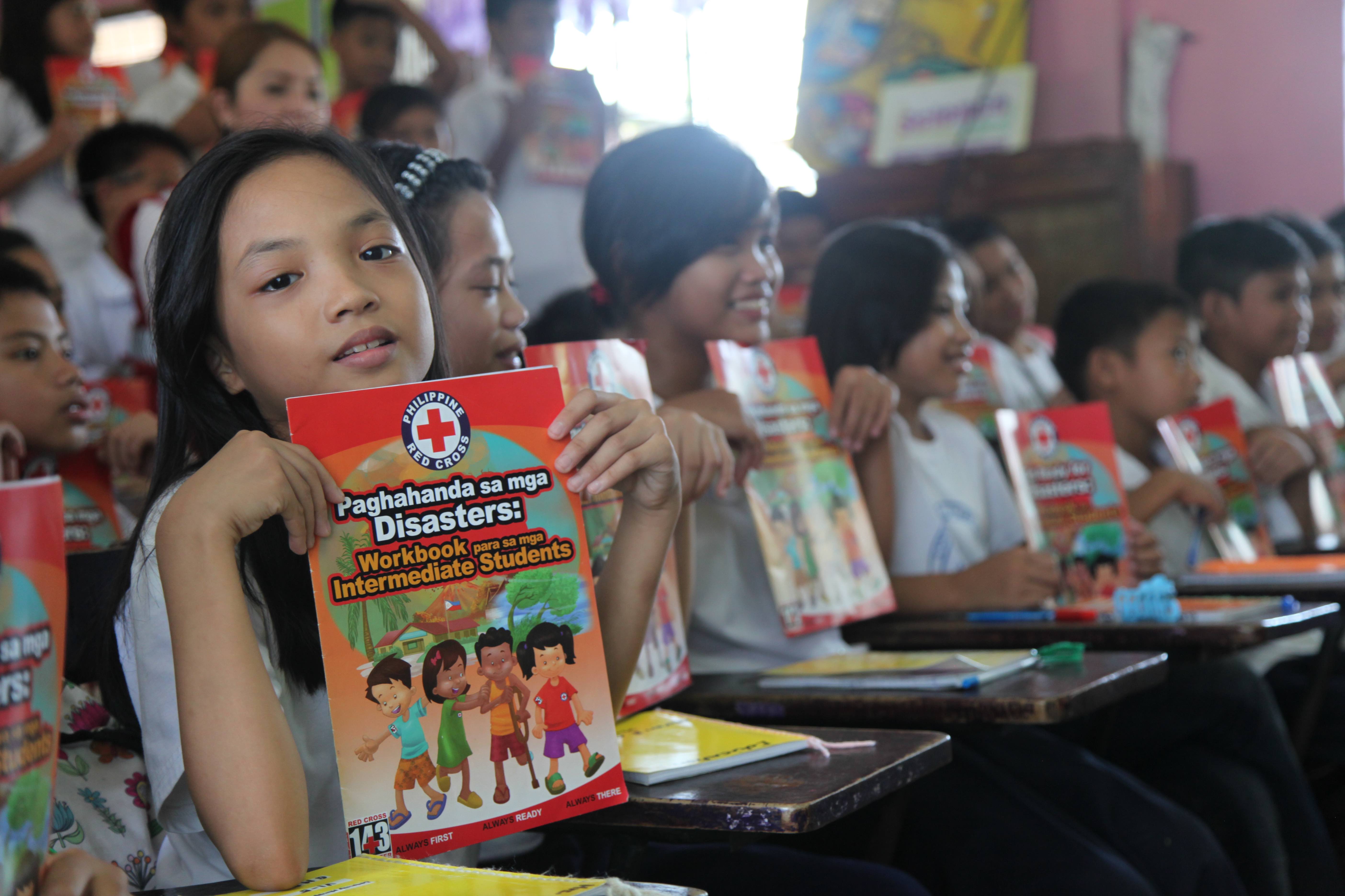A young girl holds up a workbook that she used as part of a disaster risk reduction education program at the Santulan Elementary School near the capital of Manila in the Philippines. 