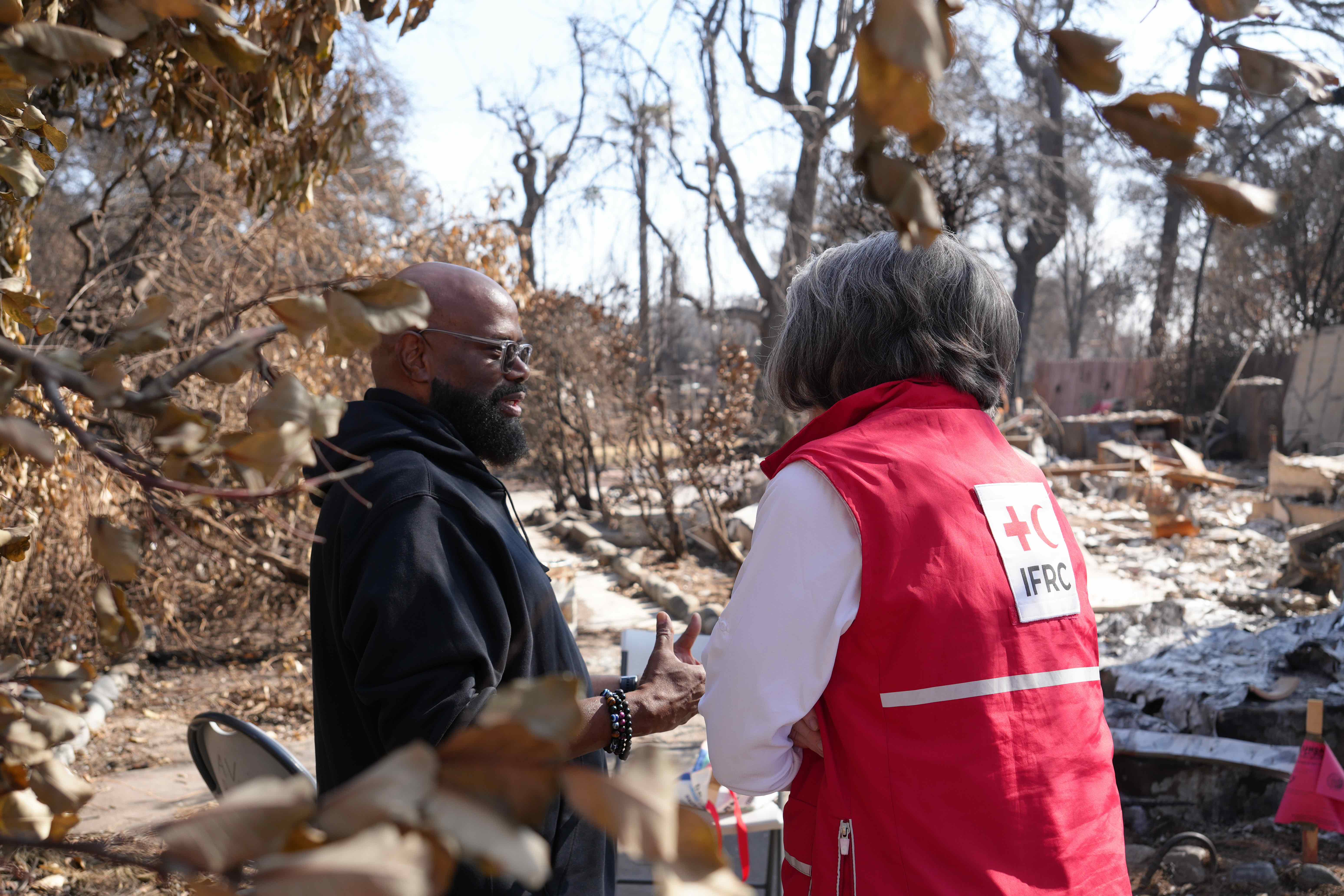 La presidenta de la IFRC, Kate Forbes, habla con un hombre que perdió su casa durante los recientes incendios forestales que arrasaron gran parte de Los Ángeles, California. 