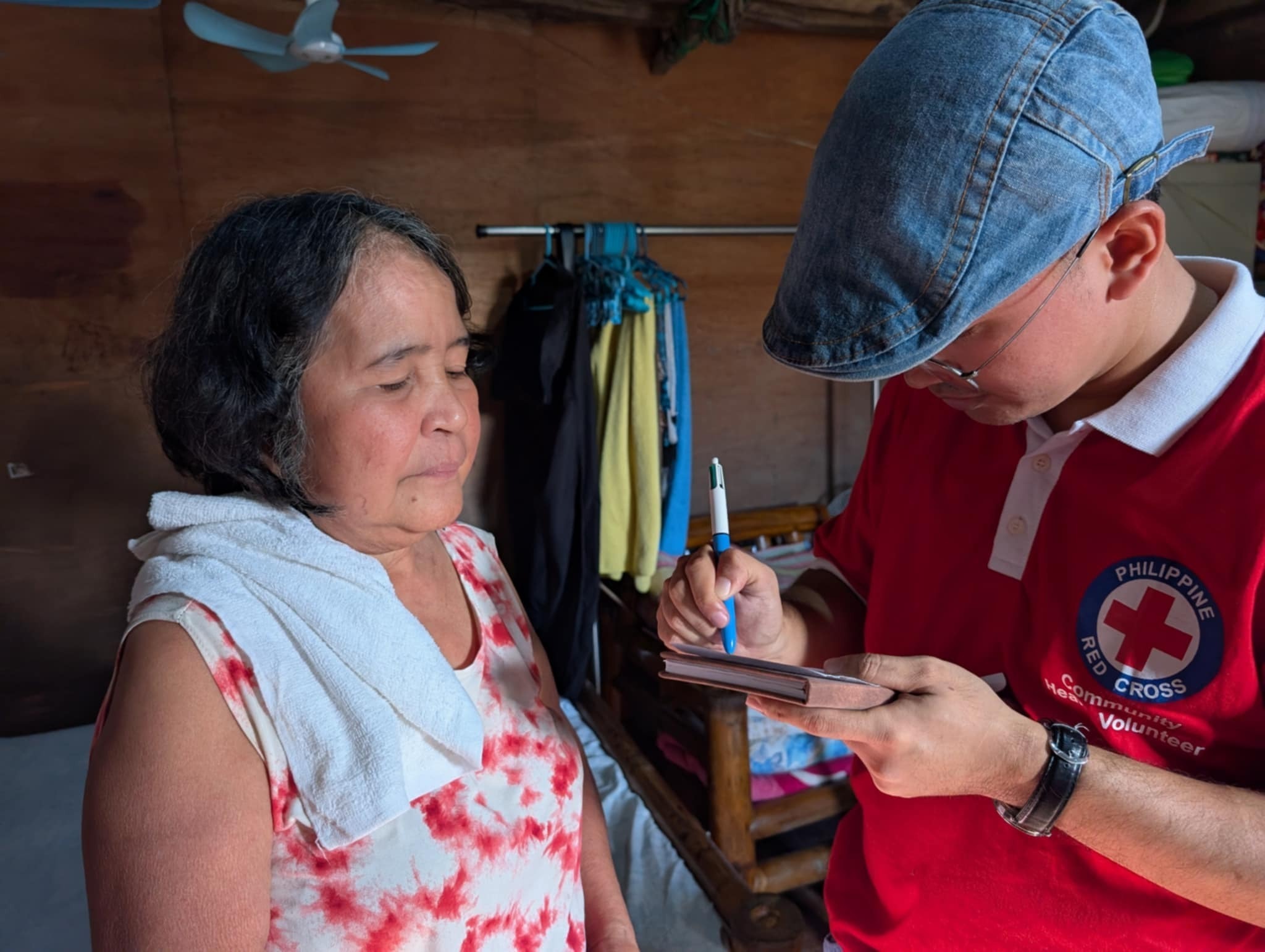 Philippines Red Cross volunteer James Asma speaks to Ninita, who received support from Philippine Red Cross in her home in Borongborgon, Camarines Sur, which was hit hard by the successive typhoons.