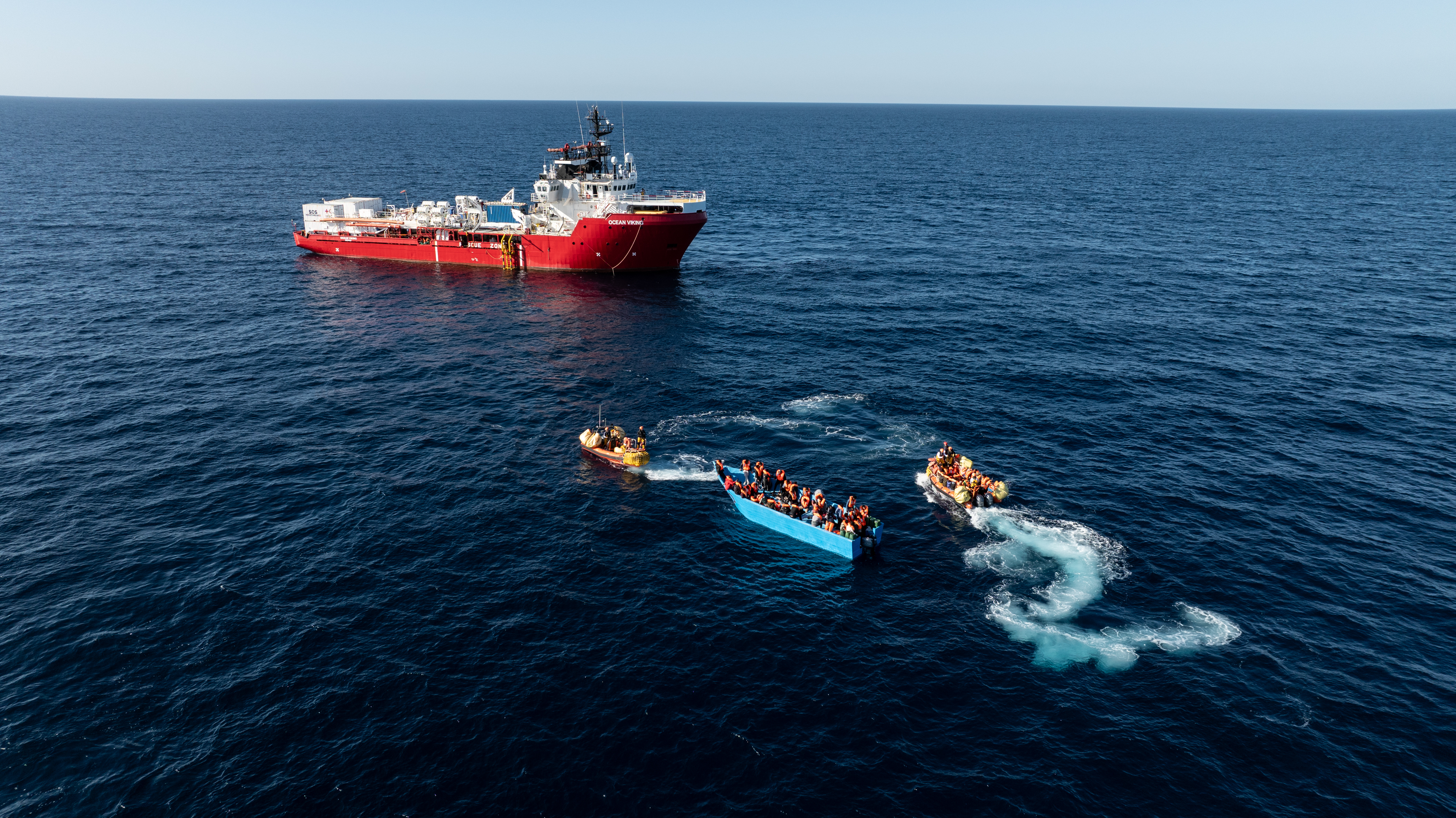 Crewmembers from The Ocean Viking use small motorboats to rescue migrants from a boat in distress.