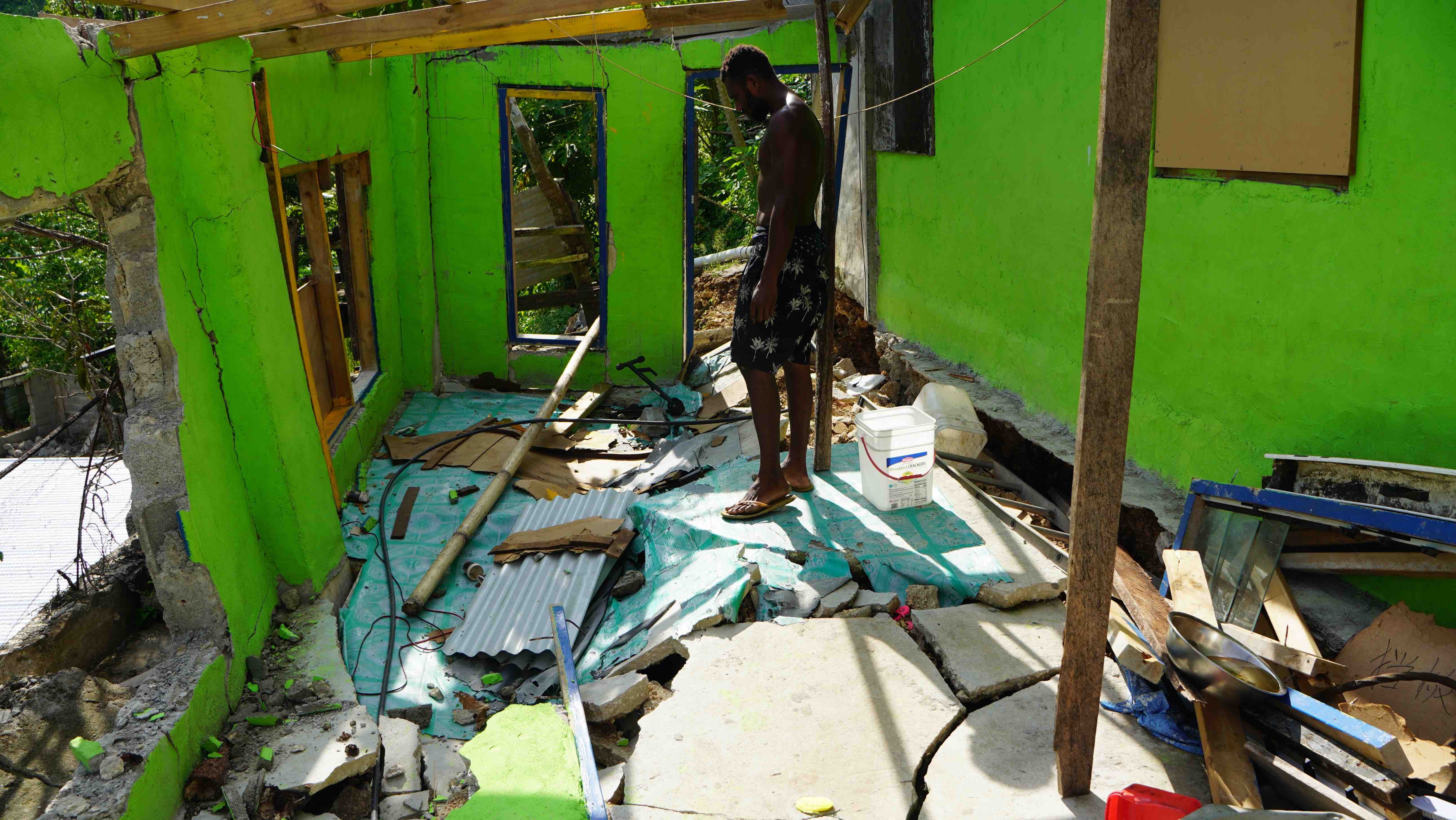 A man stands inside what's left of his home following the December 17 earthquake and its many aftershocks.