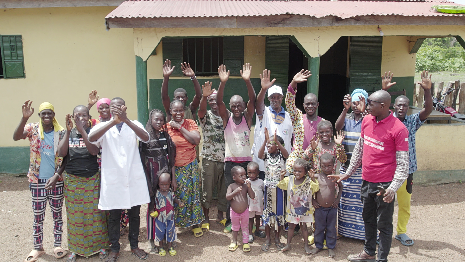 Les habitants du village de Kabayaba, en Guinée, se tiennent devant leur nouveau poste de santé qu'ils ont construit avec l'aide de la Croix-Rouge guinéenne afin d'améliorer leur accès aux services de santé et de réduire les risques d'épidémies.