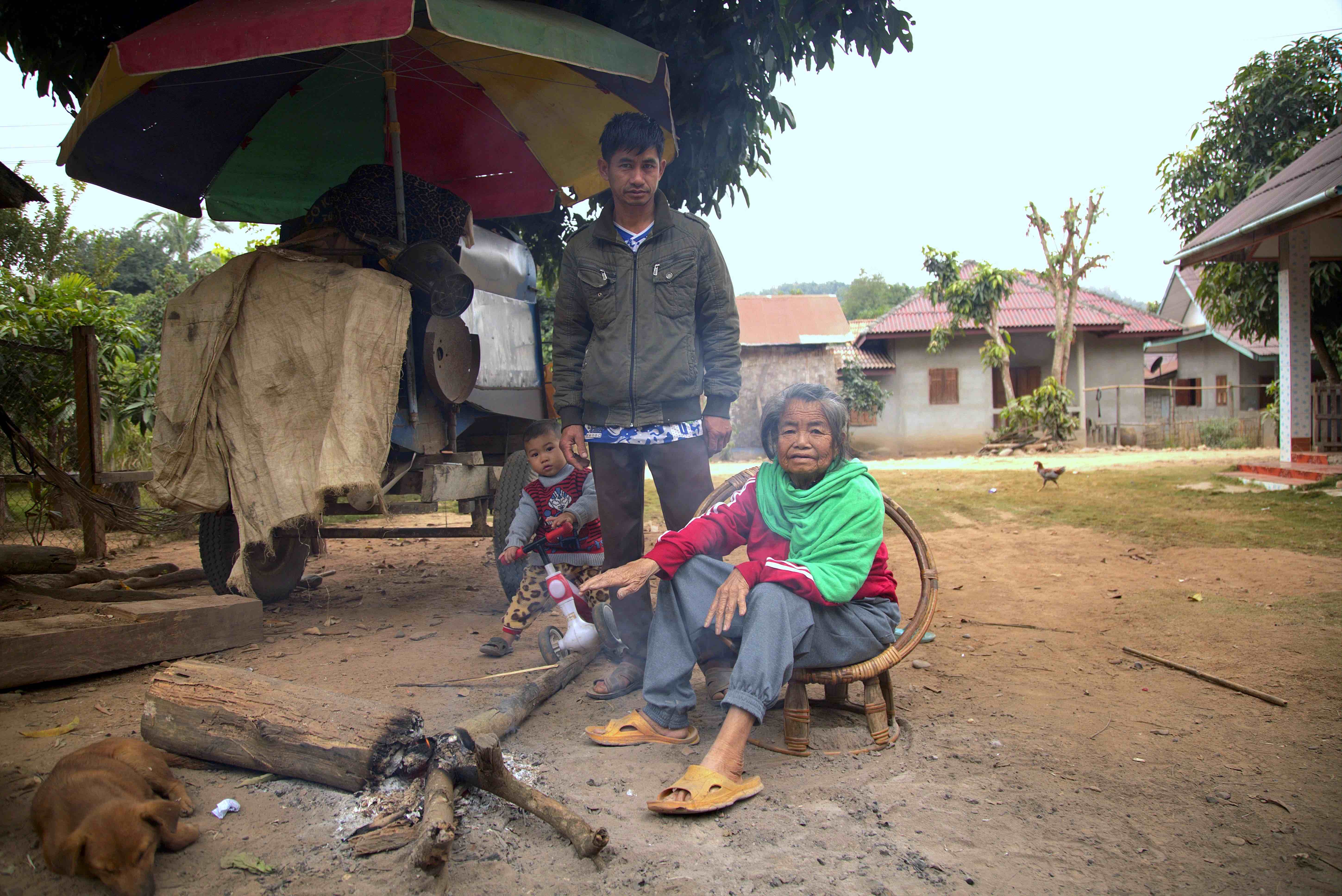 Keokaen with his 85-year-old mother and two-year-old son gathering around a small fire near their home.