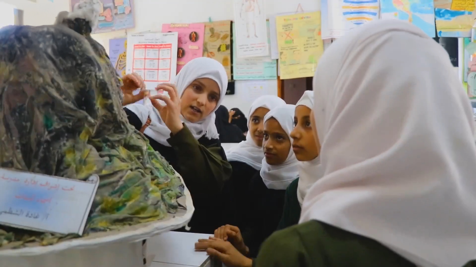 Alif explains her science project – a paper maché model of a volcano – to other students at the Asmaa School for Girls in the city of Dhamar, Yemen. 