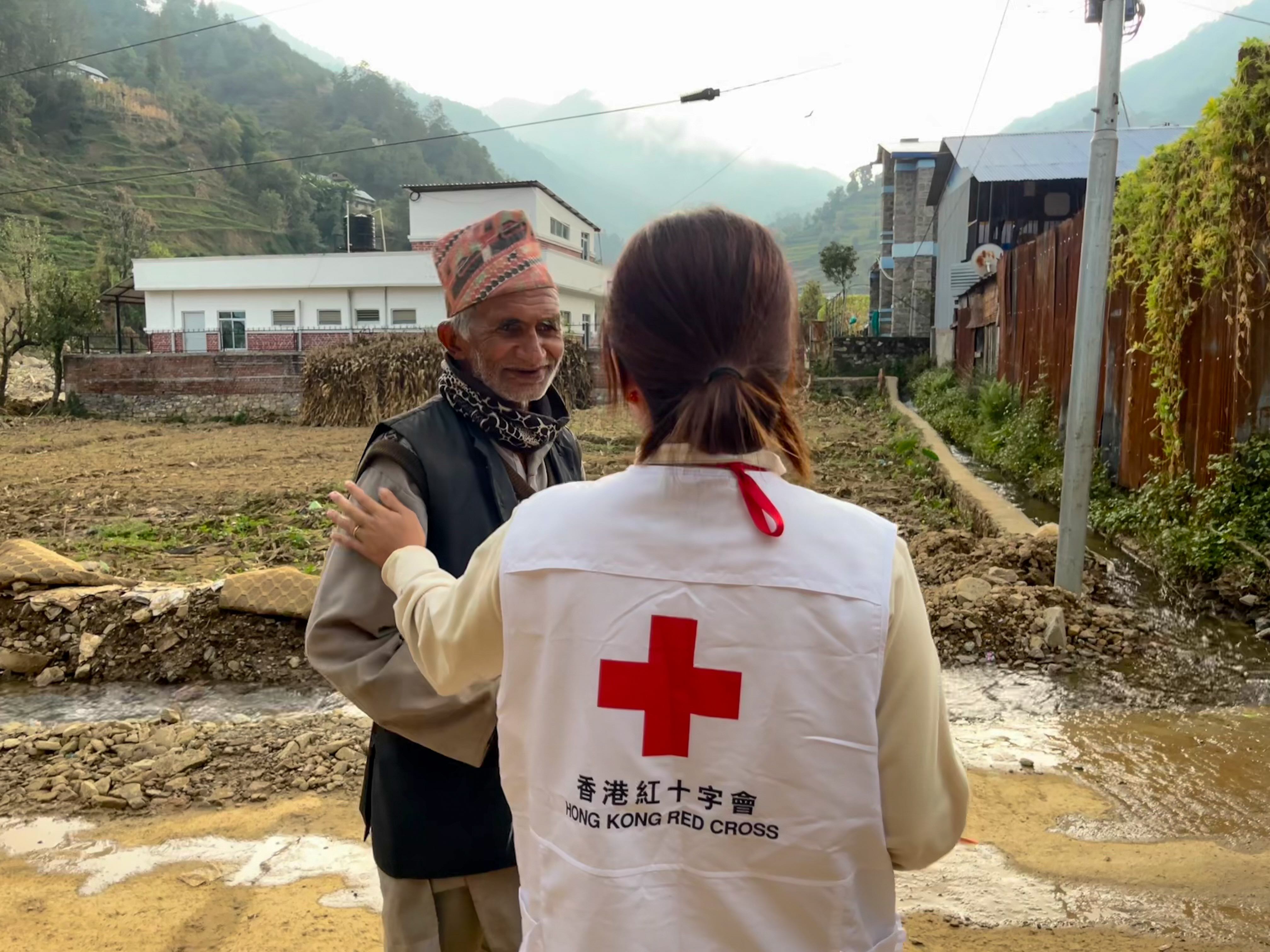A Red Cross workers listens to the story of independent farmer Gopi Lal Sapkota who stands near his home, partially buried by mud and rocks. Flash floods also wiped out his crops and the harvest he had stored from last year.