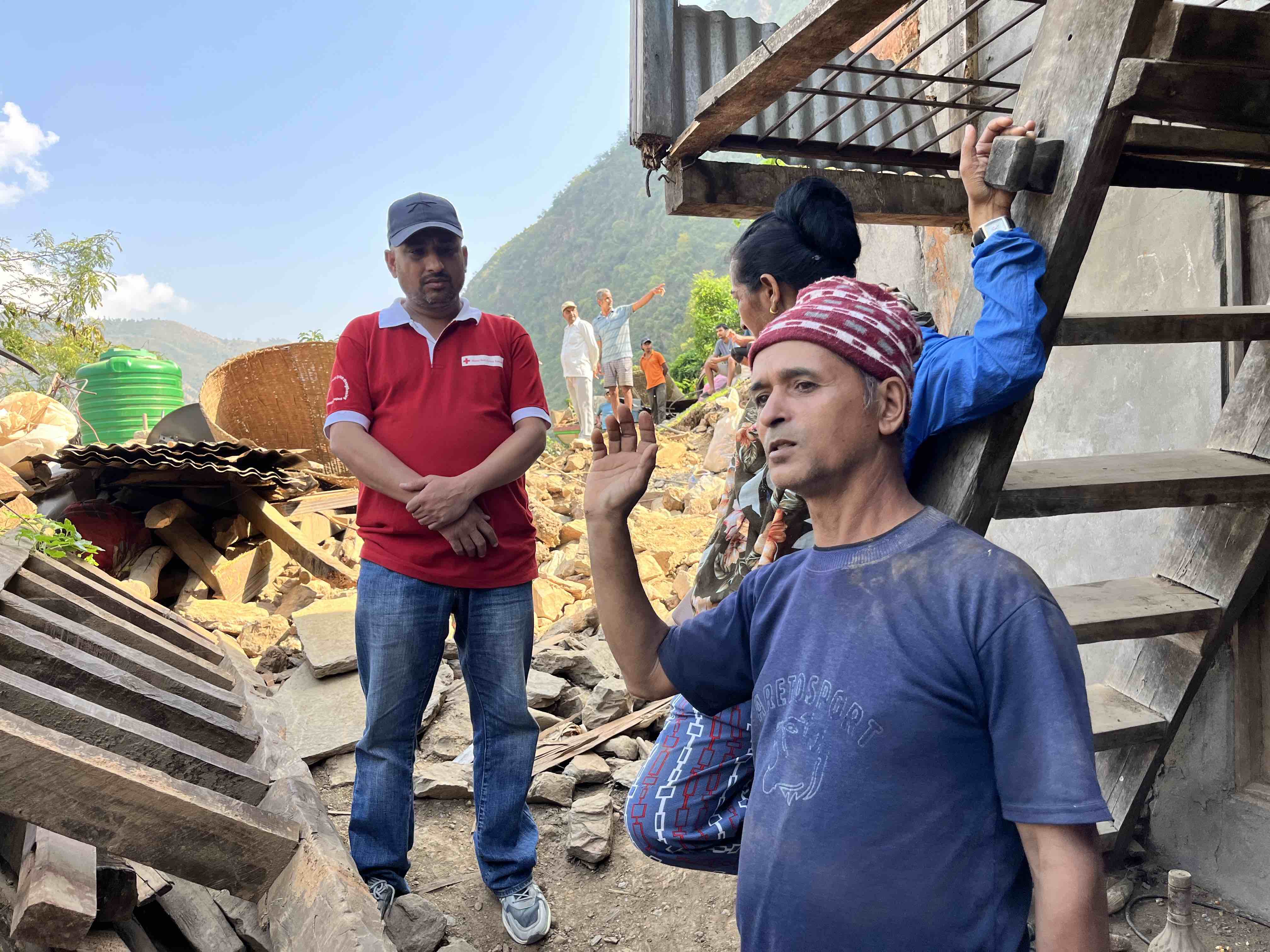 A volunteer with the Nepal Red Cross listens as a local husband and wife, named Bohd and Binda, explain how they tragically lost their 12-year-old eldest son in last year’s flash flood.