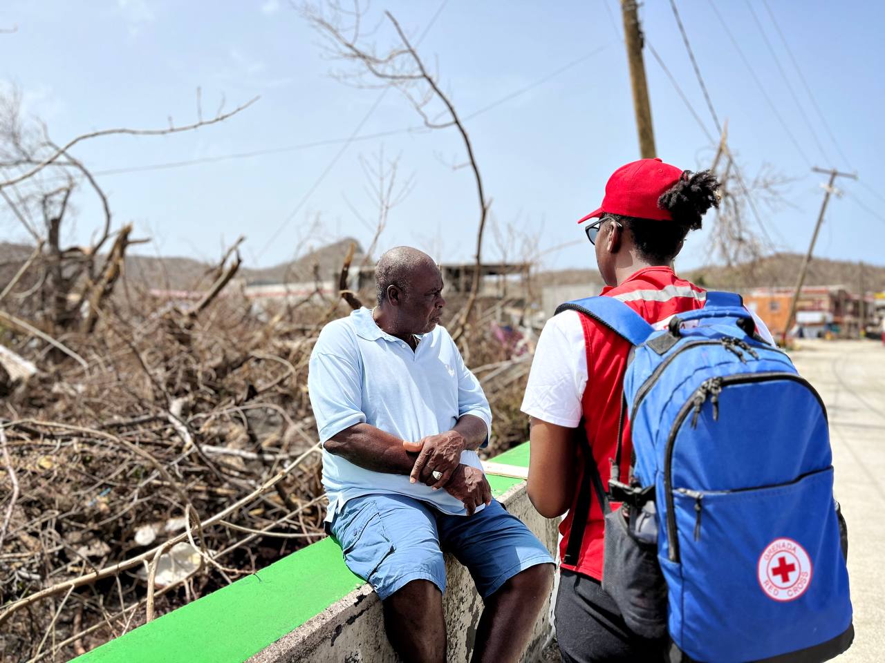 A Grenada Red Cross volunteer speaks with a man affected by Hurricane Beryl in July 2024 to assess damage and needs.