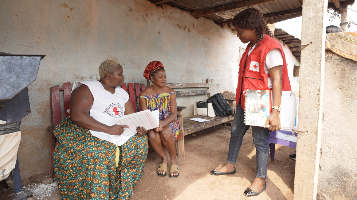 Irene (left) and Rachel (right) from the Cameroon Red Cross speak to Najassa from Bamvele about her mother who was struggling with acute watery diarrhoea for several days.