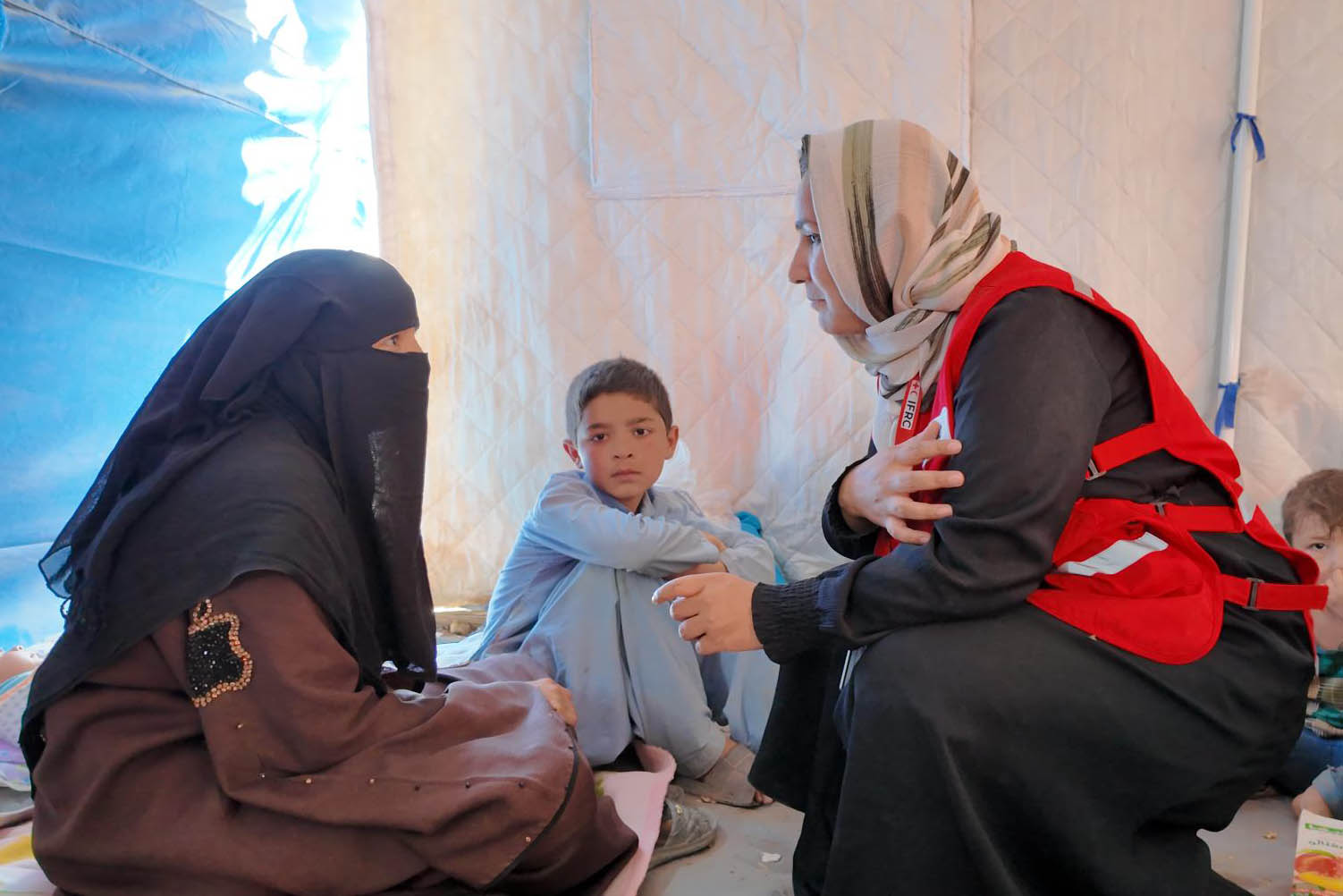 Salima, una madre afgana de 31 años, sostiene a su recién nacida en una tienda de campaña en la frontera de Spin Boldak tras regresar recientemente de Pakistán. La IFRC, junto con la Media Luna Roja Afgana, la apoya a ella y a otras personas que atraviesan dificultades similares.