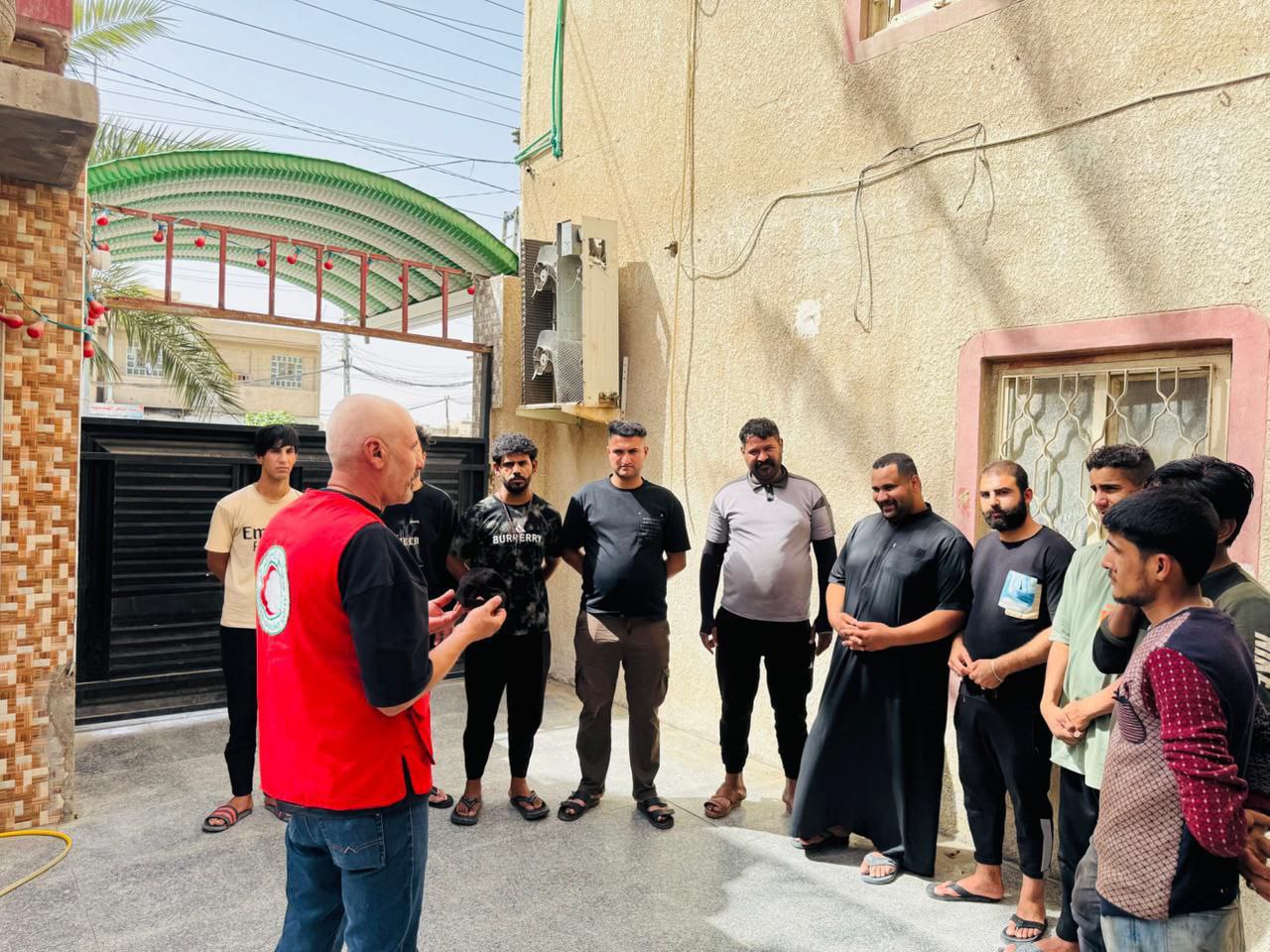 A volunteer for the Iraqi Red Crescent talks to a group of men about how to protect themselves and their families from the dangers of extreme heat.
