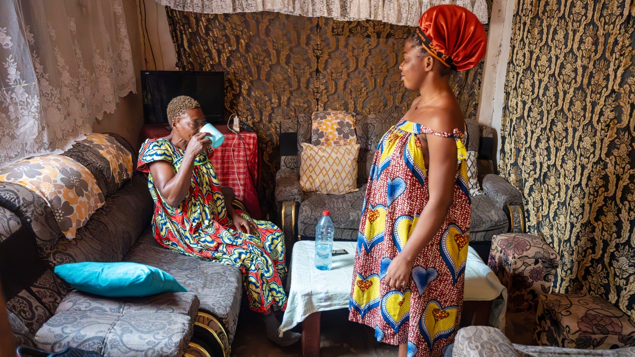 Najassa stands by as her mother drinks the Oral Rehydration Solution she prepared to help her recover from AWD.