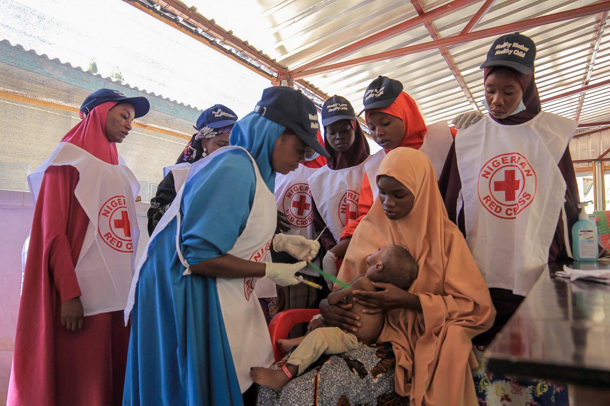 Nigerian Red Cross volunteers provide care to a child suffering from acute malnutrition.