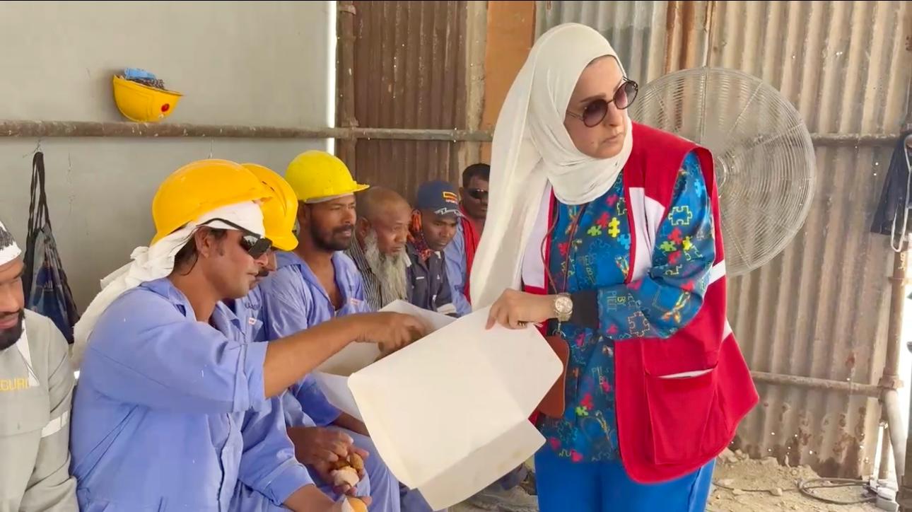 A volunteer with the Bahrain Red Crescent Society visits with construction workers who are exposed to high daytime temperatures during their daily work to share information and supplies that can help them prevent heat stroke and heat exhaustion.