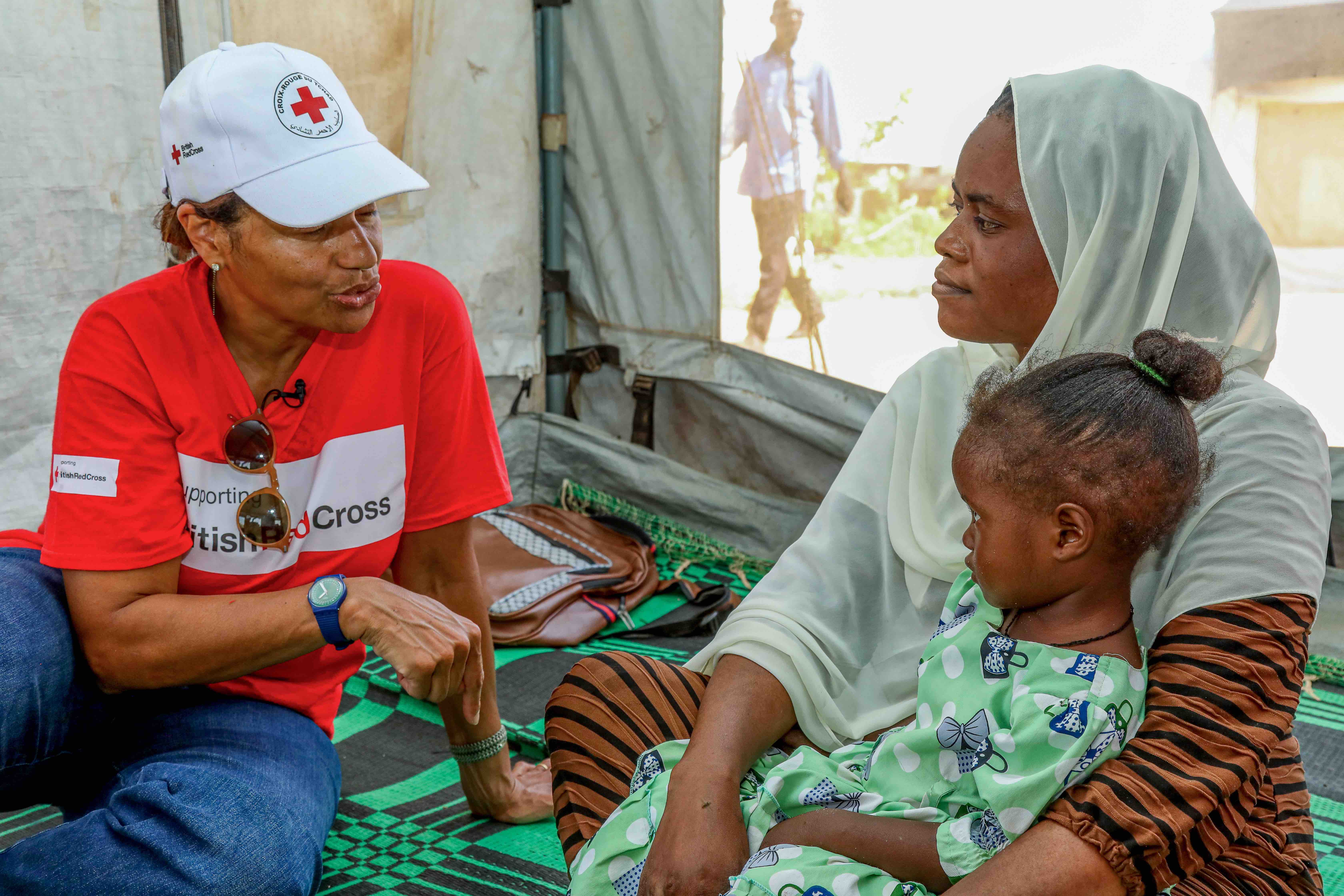 A British Red Cross team member speaks with 24-year-old Munana, who had to flee her home in Sudan’s Darfur region with her children in 2024.