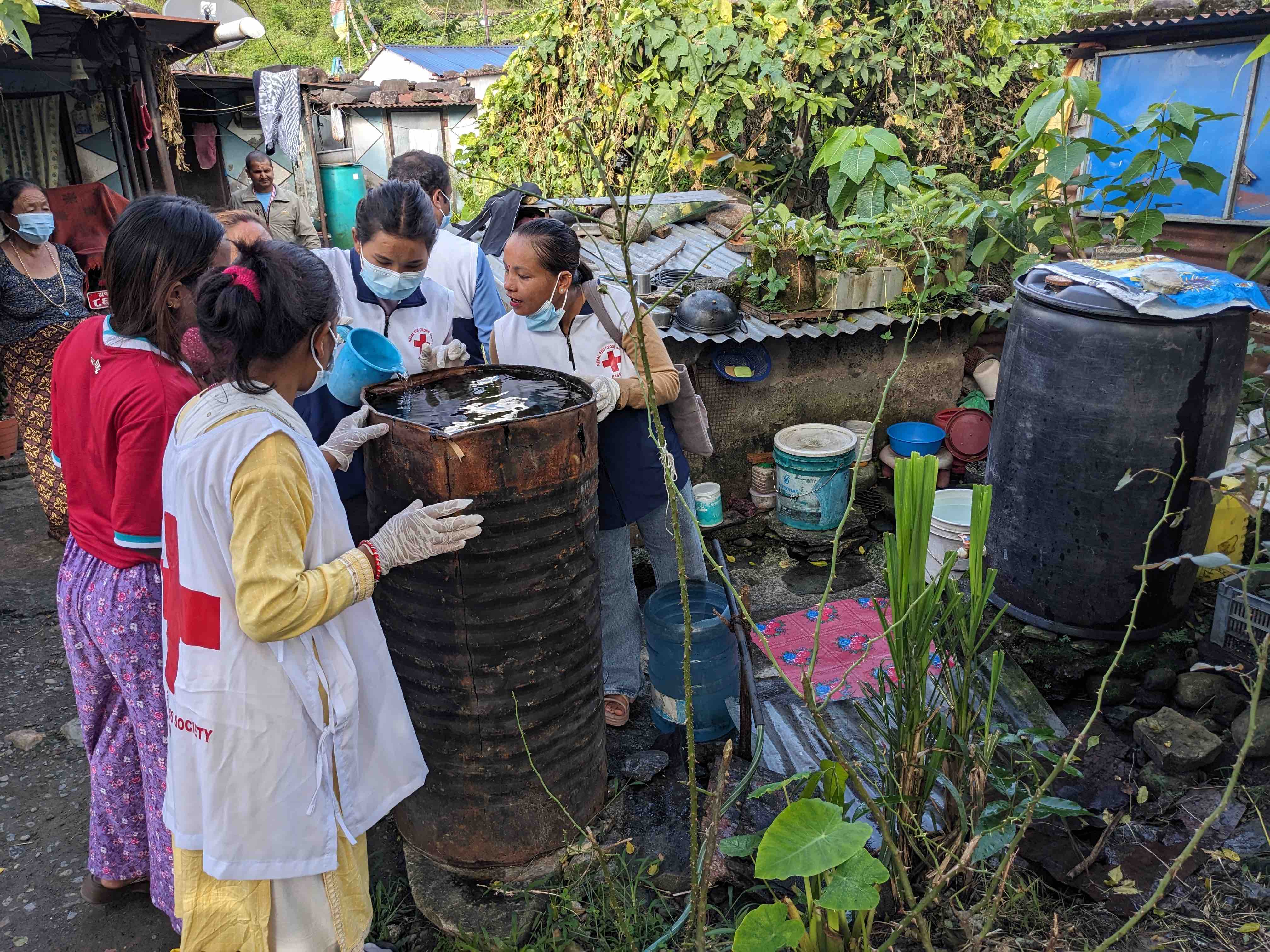 Volunteers from the Nepal Red Cross Society treat a barrel that contained stagnant water to prevent infestation of Dengue-bearing mosquitos that often breed in standing water.
