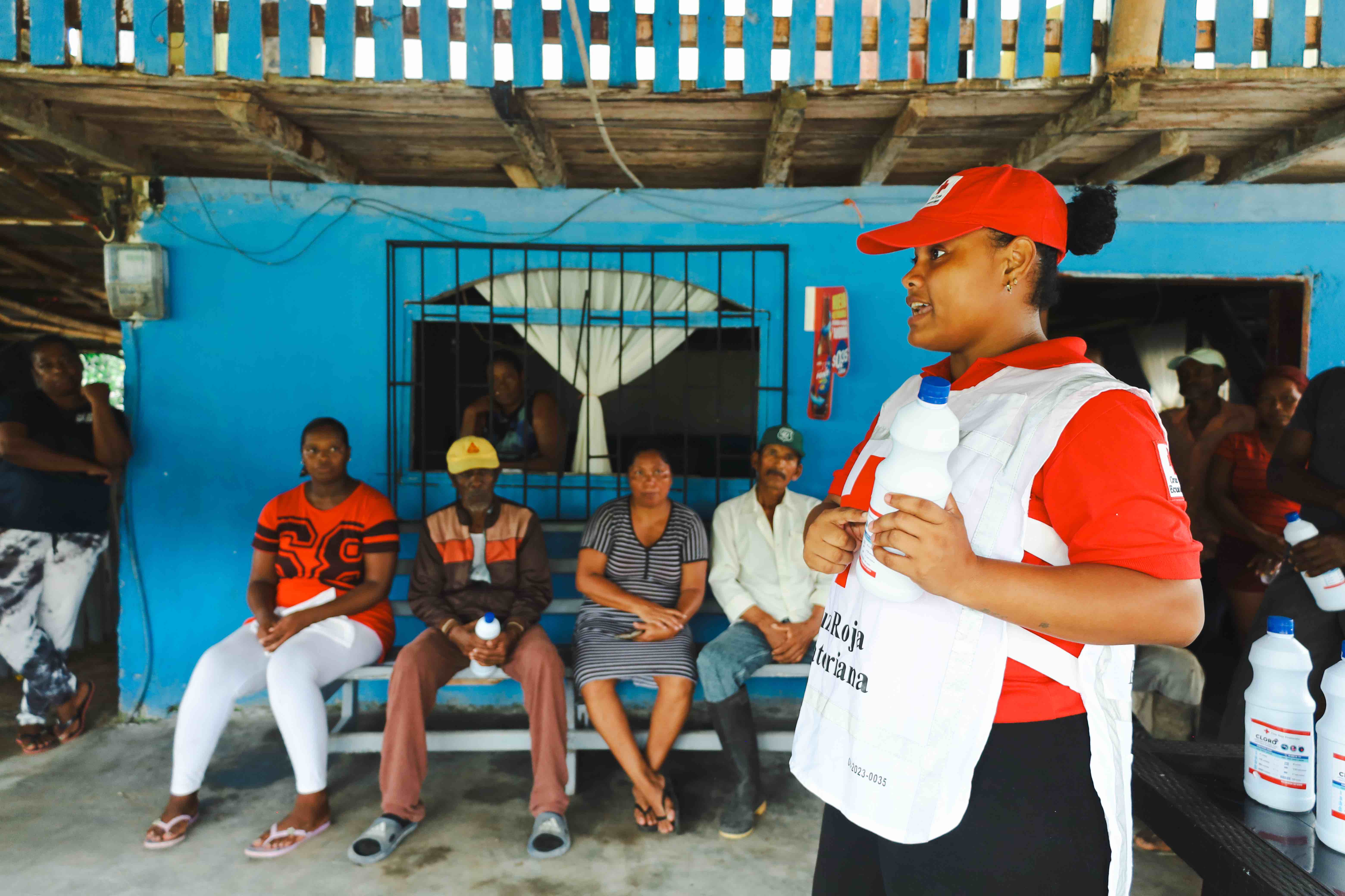 A local volunteer from the Esmeraldas branch of the Ecuadorian Red Cross explains how the home chlorination process works.