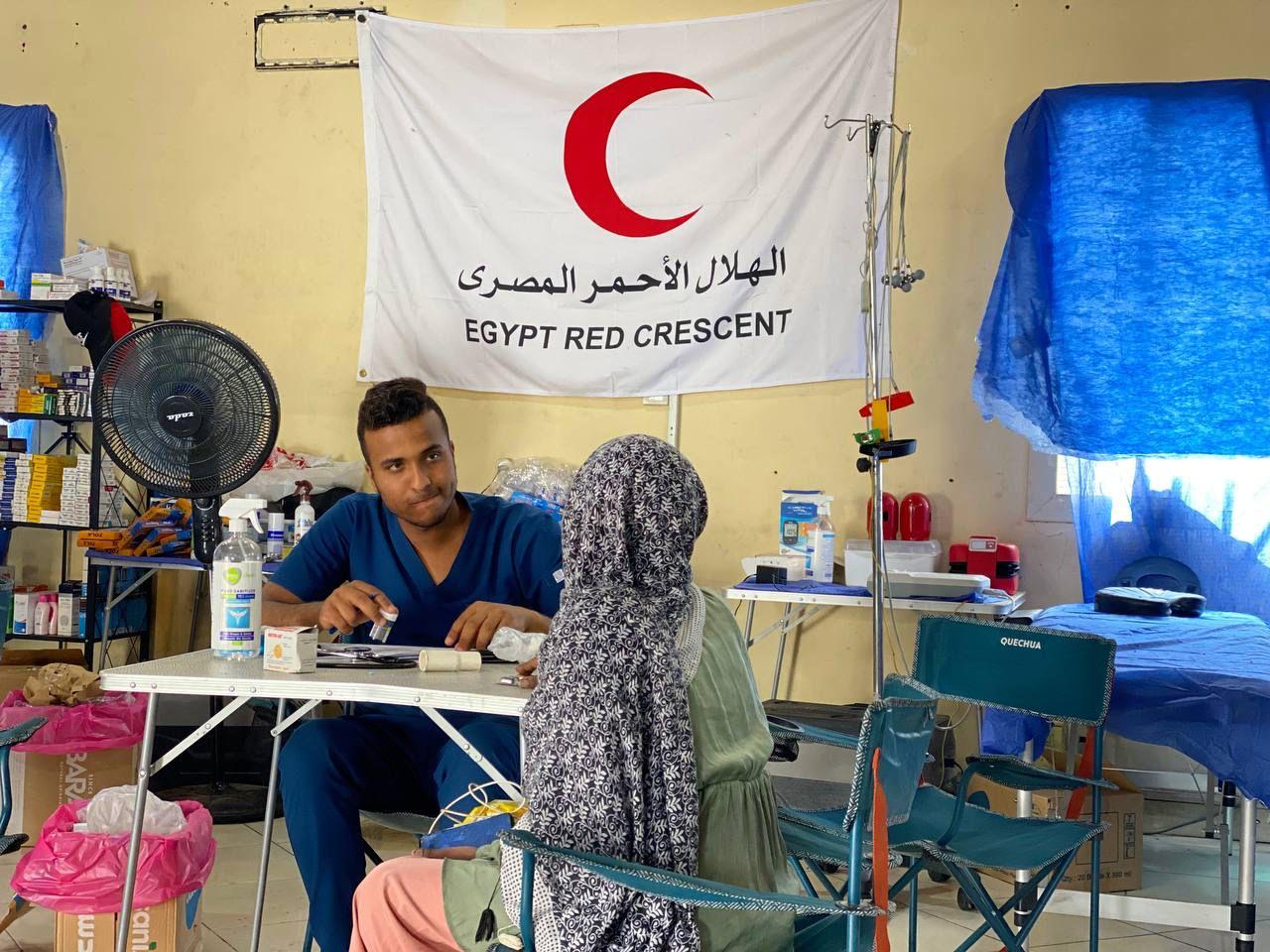 A volunteer with the Egyptian Red Crescent does a health check up with a woman who recently arrived in Qustul, in southern Egypt, after fleeing ongoing violence in Sudan.