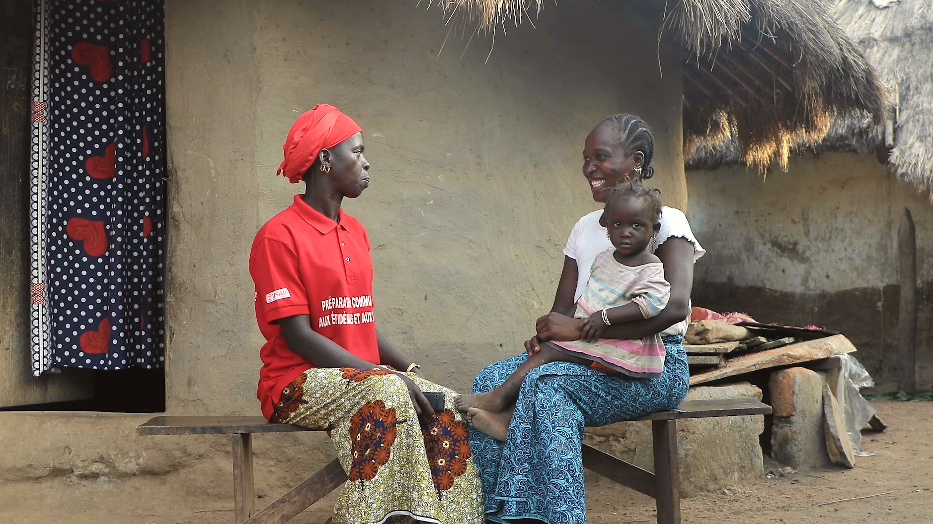 A Guinean Red Cross volunteer speaks to a mother and her daughter in Dalafilani about different disease risks.