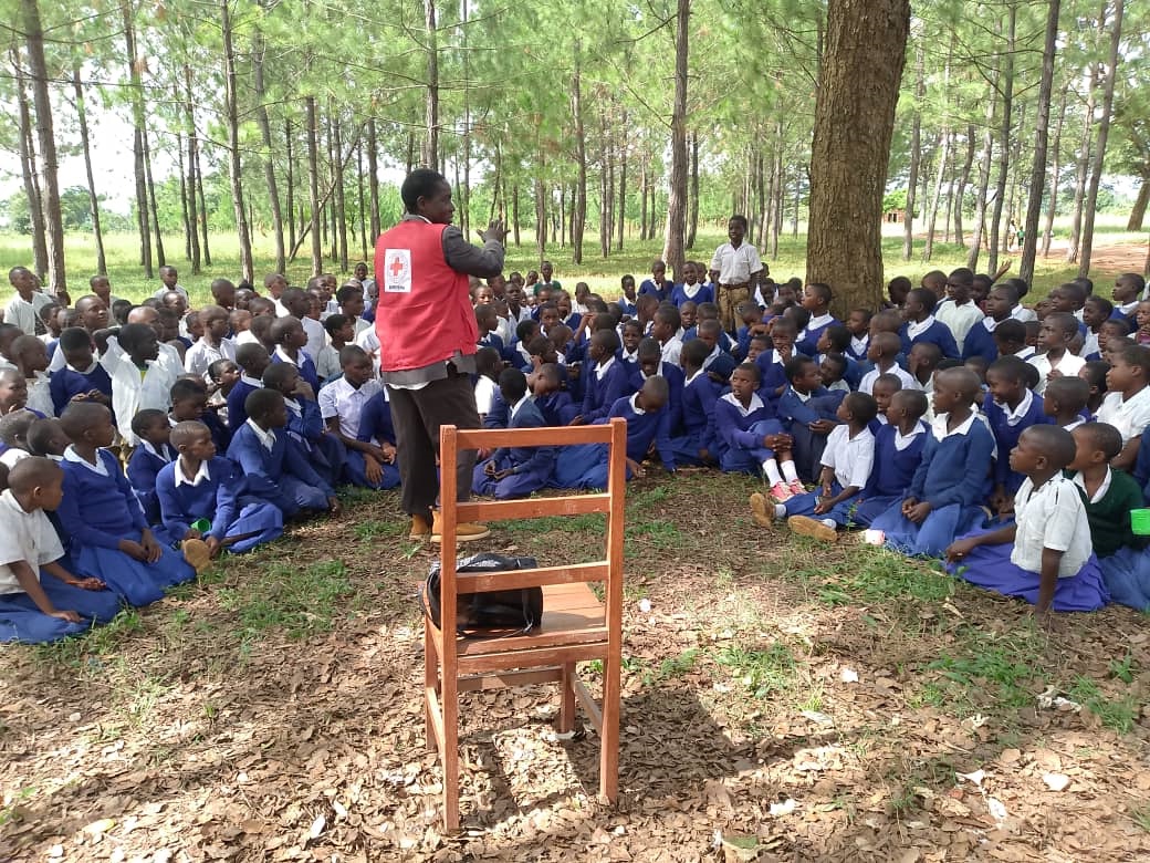 A volunteer with the Tanzania Red Cross talks to school children about how to protect themselves from Marburg virus disease and to address common misconceptions about how it is spread.