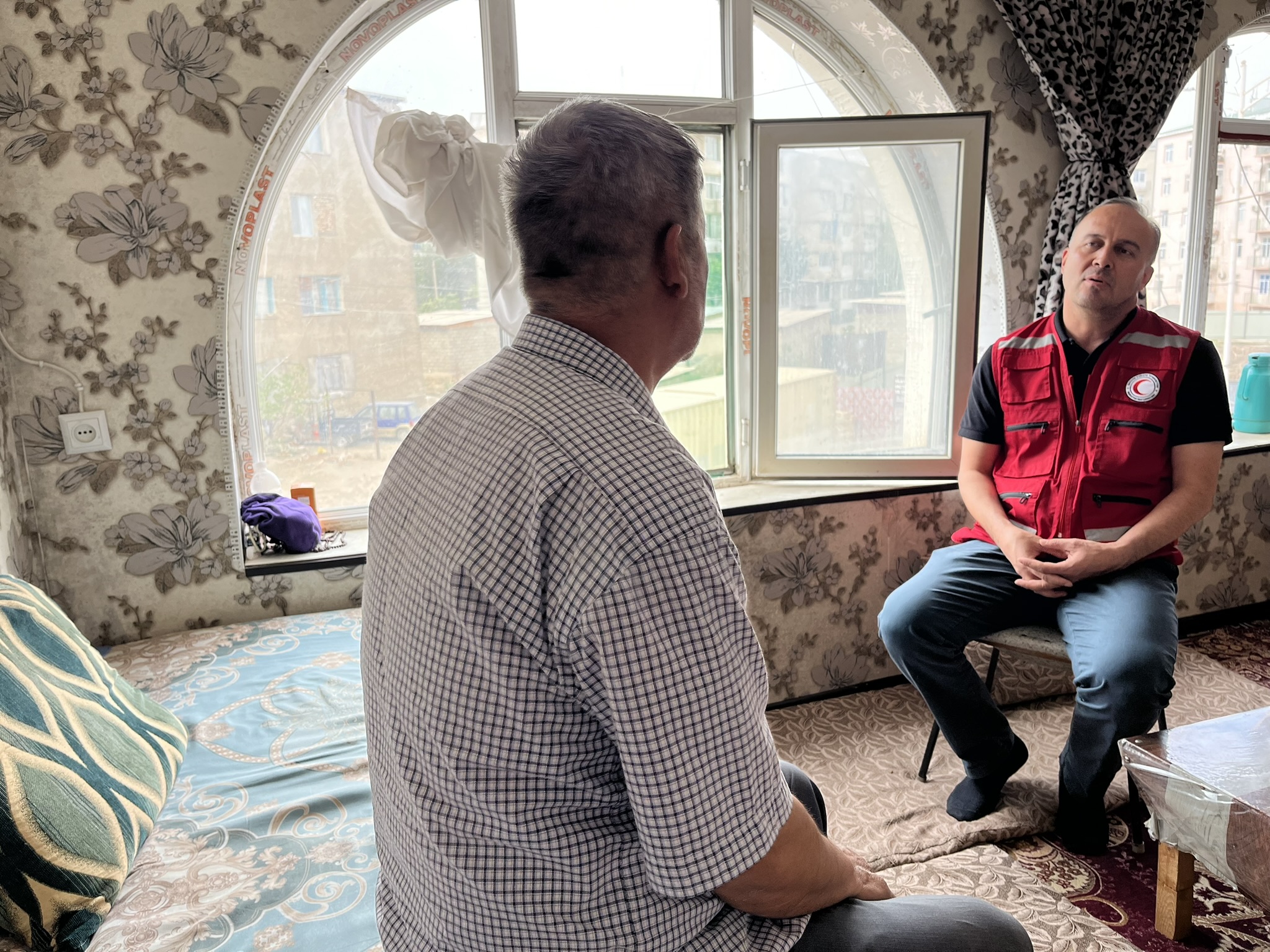 A volunteer with the Tajikistan Red Crescent Society talks with Masoud, who fled Afghanistan with his family in 2021.