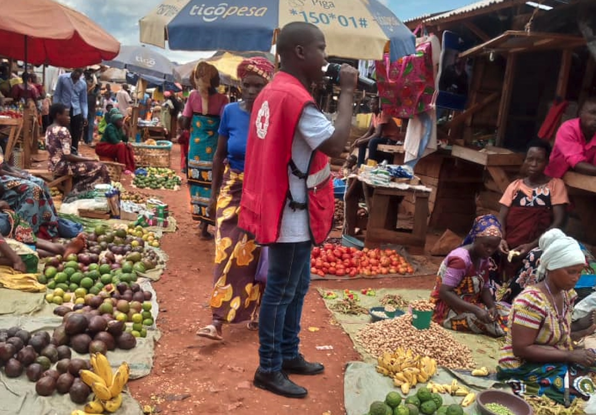 A volunteer from the Tanzania Red Cross takes to the streets with a megaphone in a busy city market to warn people about the dangers of Marburg, as well as how to prevent, detect and respond to the disease.