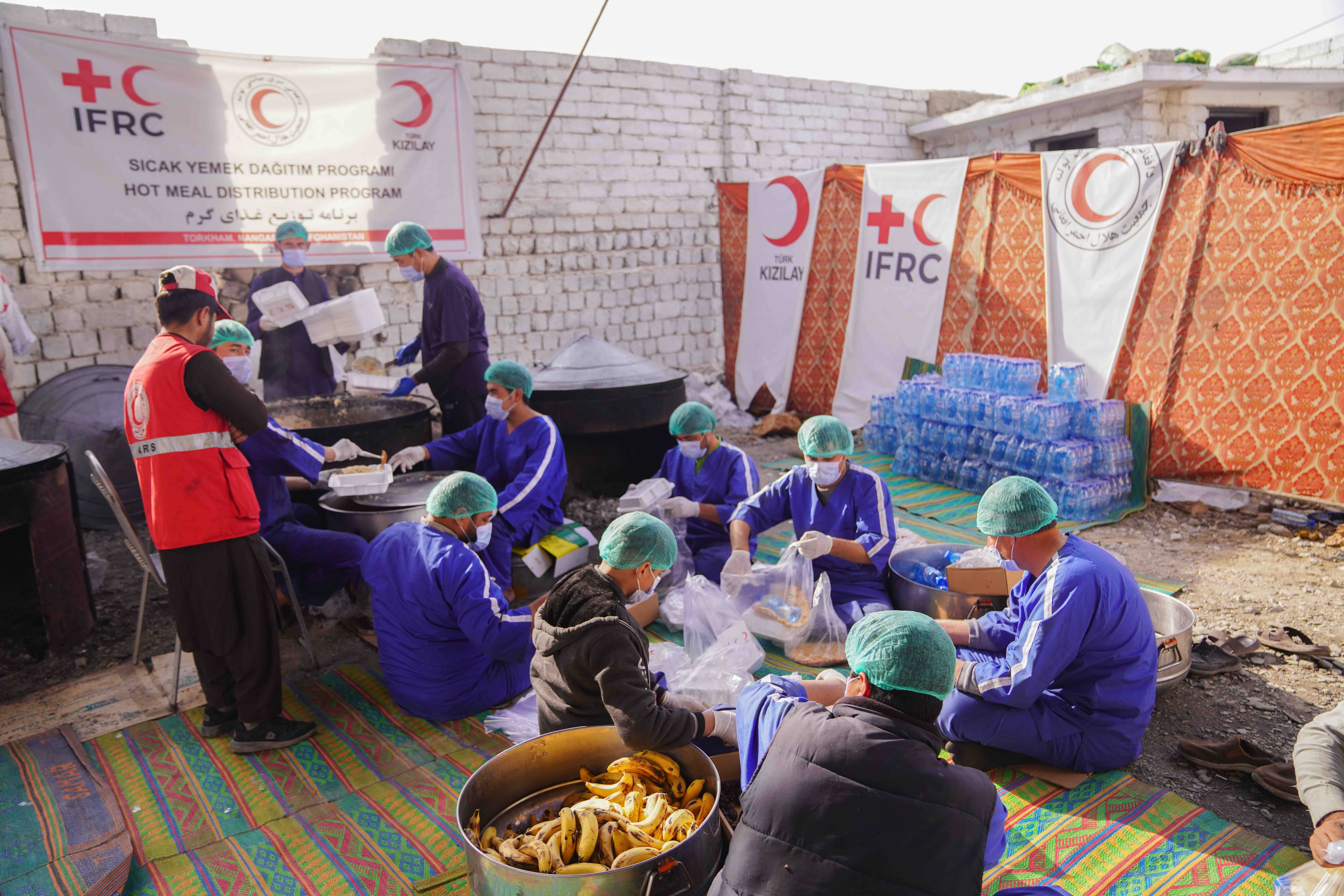 A team of Afghan Red Crescent volunteers distribute hot meals they’ve prepared to people who have had to return from Pakistan. 