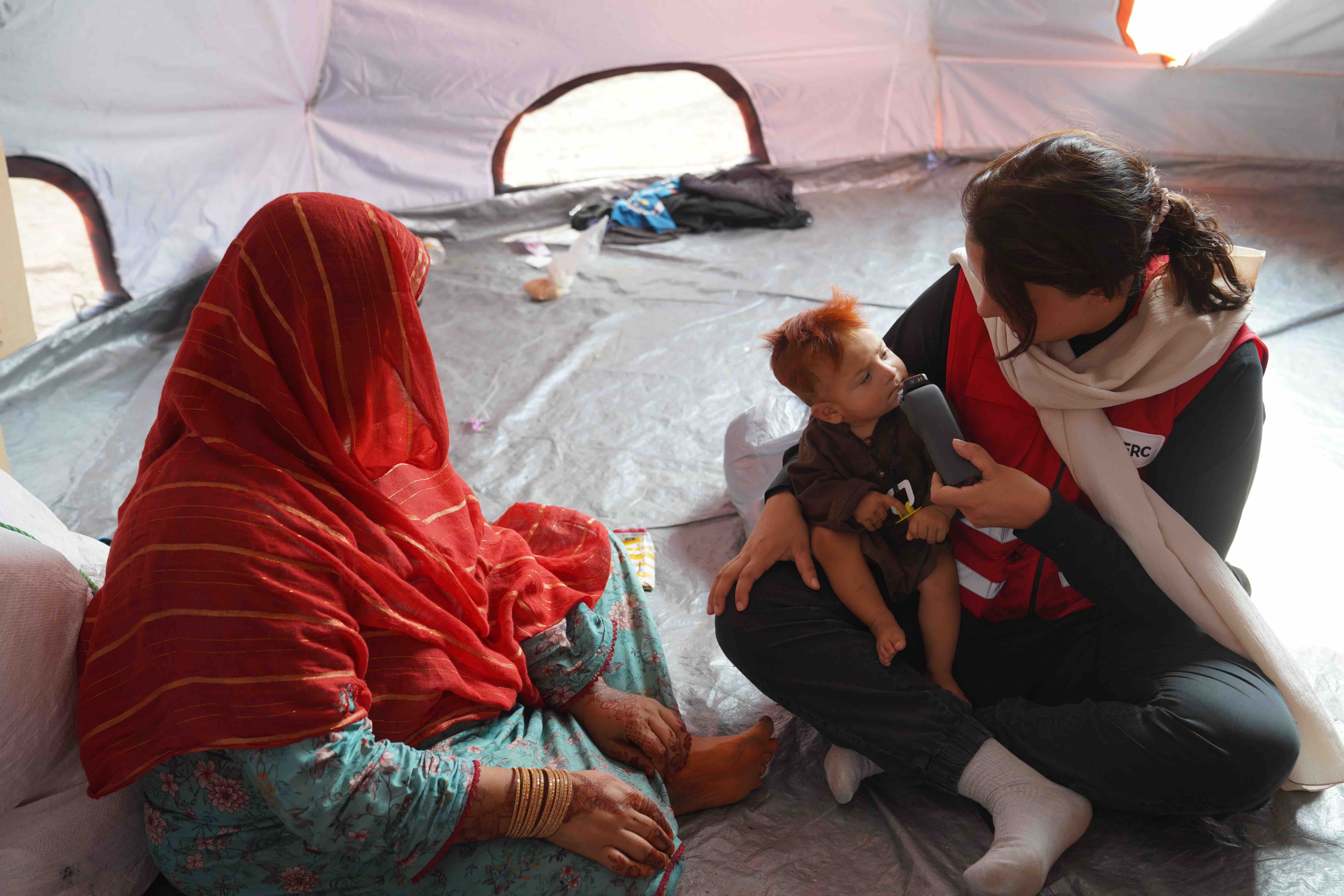 In the crowded camps along Afghanistan’s border with Pakistan, a returned Afghan mother cares for her children inside a makeshift tent provided by the Afghan Red Crescent Society.