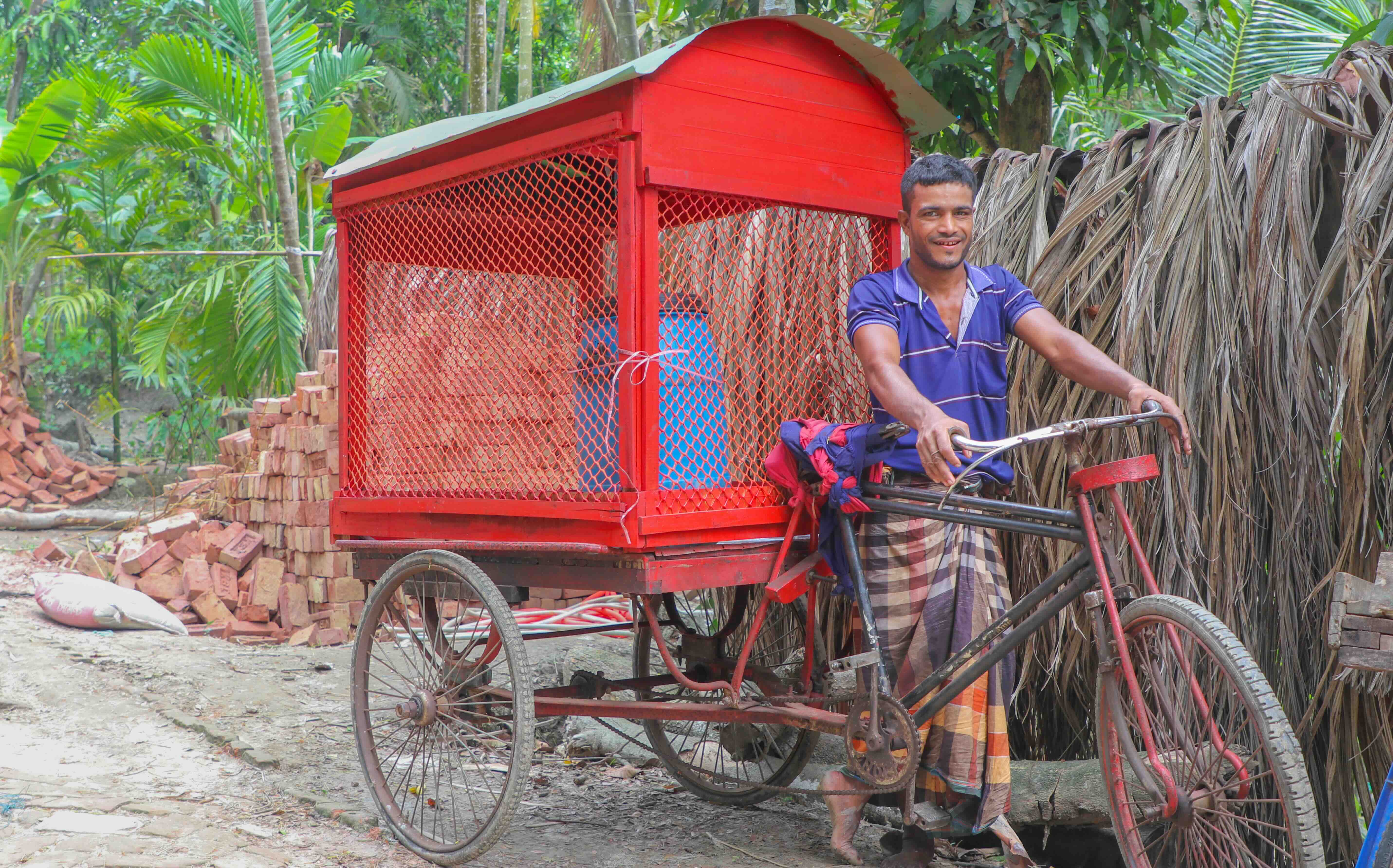 A father of three, 40-year-old Jahangir stands next to his new bright-red, bicycle powered cart, from which he sells juice at a local market. 