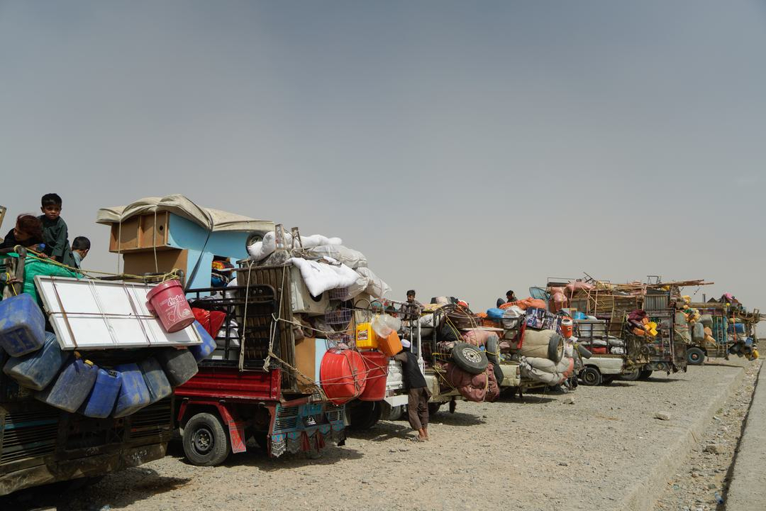 Heavily loaded trucks carrying Afghan returnees line up along the road after arriving in Kandahar from various parts of Pakistan. 