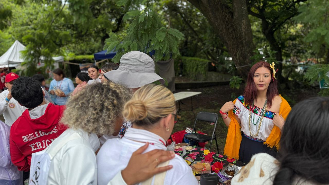 A young woman using traditional Mexican clothing shows her stand to a group of people at a cultural activity during the Mexican Red Cross Youth National Camp in Morelos, Tepoztlán. 