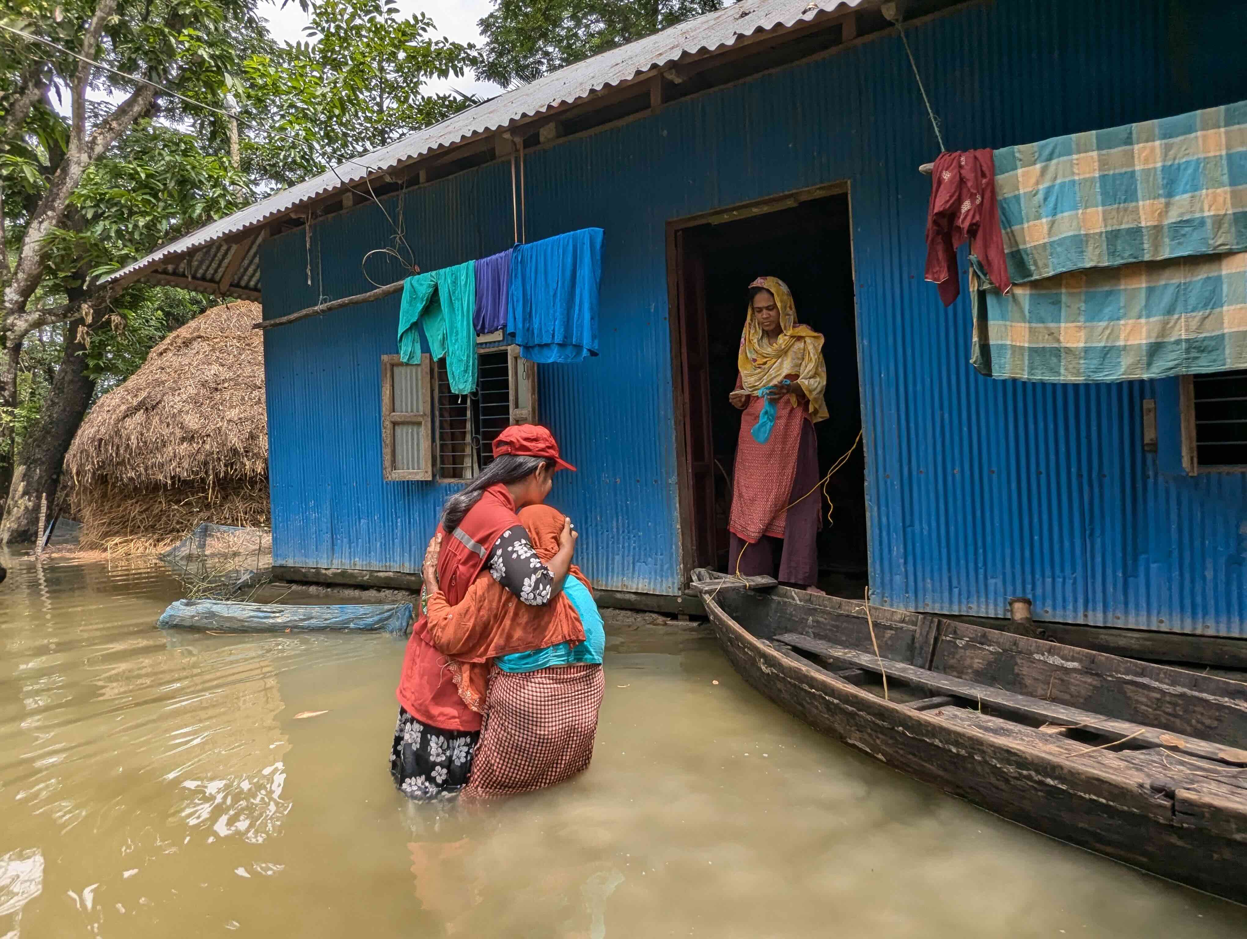  Una voluntaria de la Sociedad de la Media Luna Roja de Bangladesh consuela a una mujer cuya casa ha sido inundada por las aguas.
