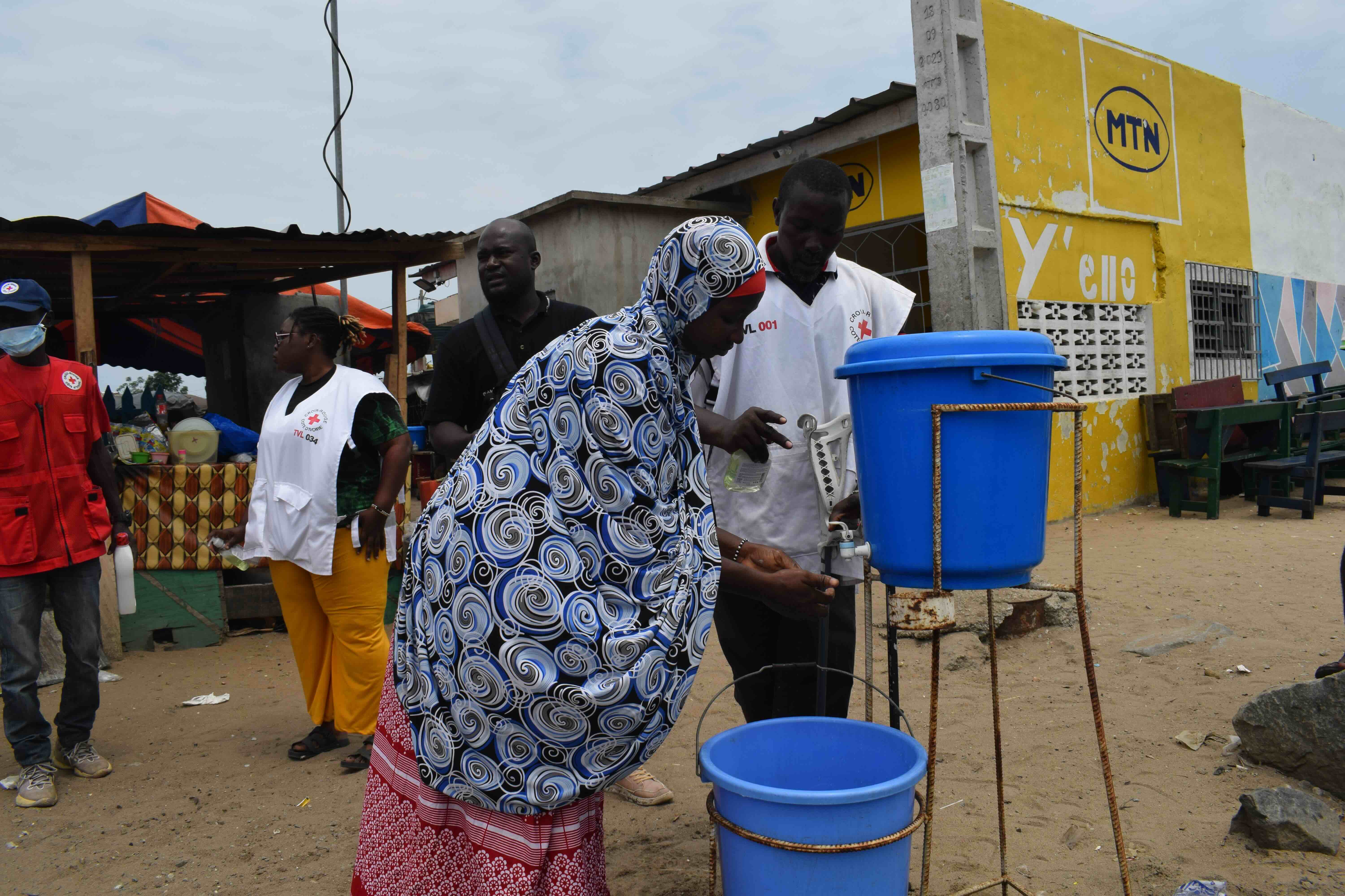 Une femme utilise un poste de lavage des mains mis en place par des volontaires de la Croix-Rouge de Côte d’Ivoire. Se laver les mains et nettoyer les surfaces fréquemment touchées est un moyen essentiel pour empêcher la propagation du choléra.