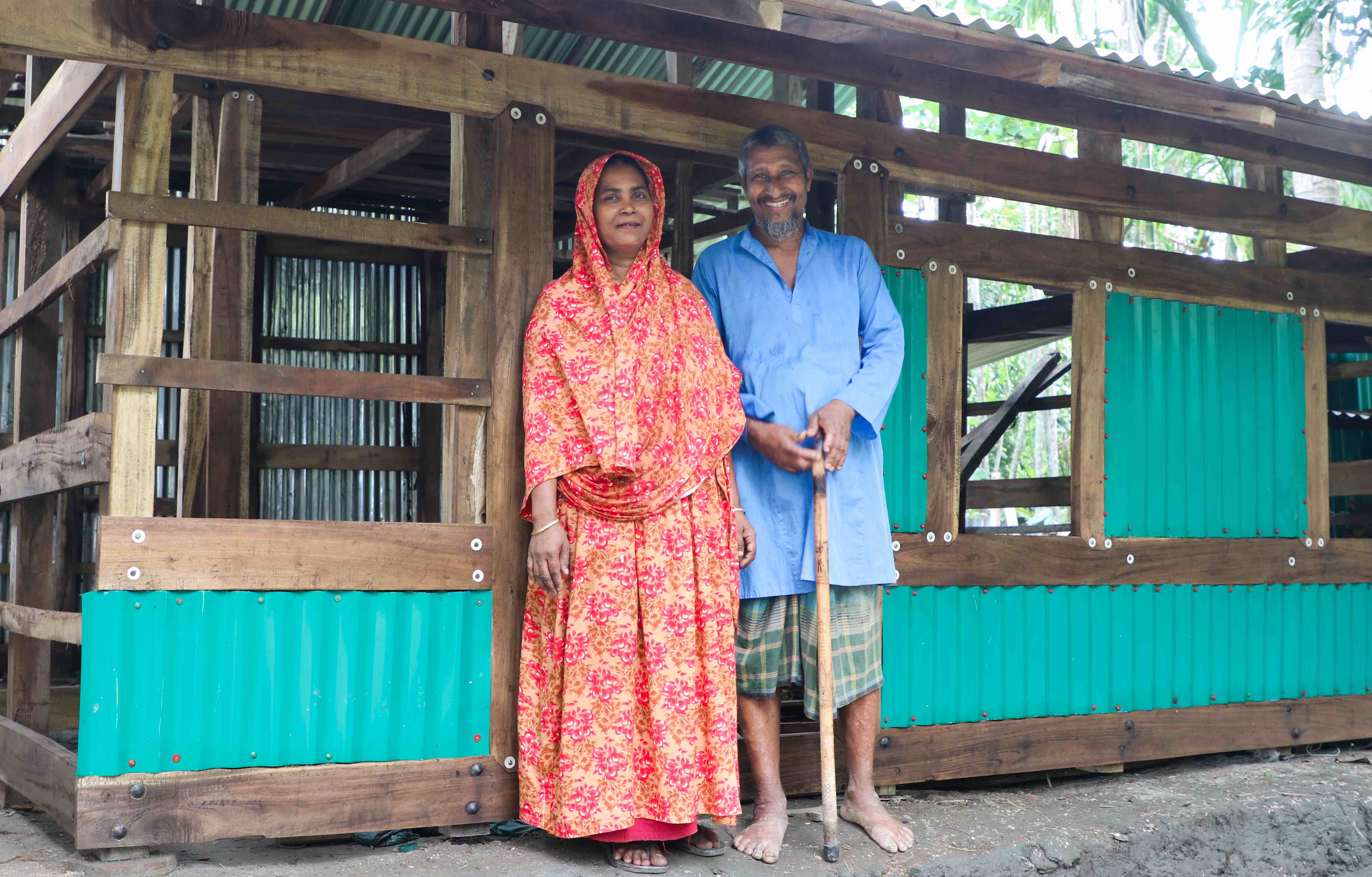 60-year-old Khalil and his wife Taslima stand in front of the home they rebuilt with support from the IFRC and the Bangladesh Red Crescent after Cyclone Remal destroyed their home in May 2024.