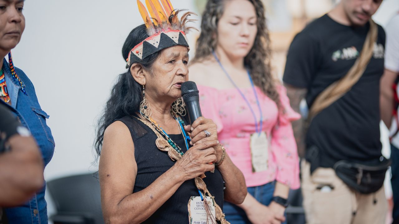 Helena López, abuela indígena de la etnia Huitoto, usa un micrófono para conducir una ceremonia de armonización en la apertura del primer diálogo de sistemas de conocimiento de la Alianza de la Cruz Roja por la Amazonía en Leticia, Colombia.