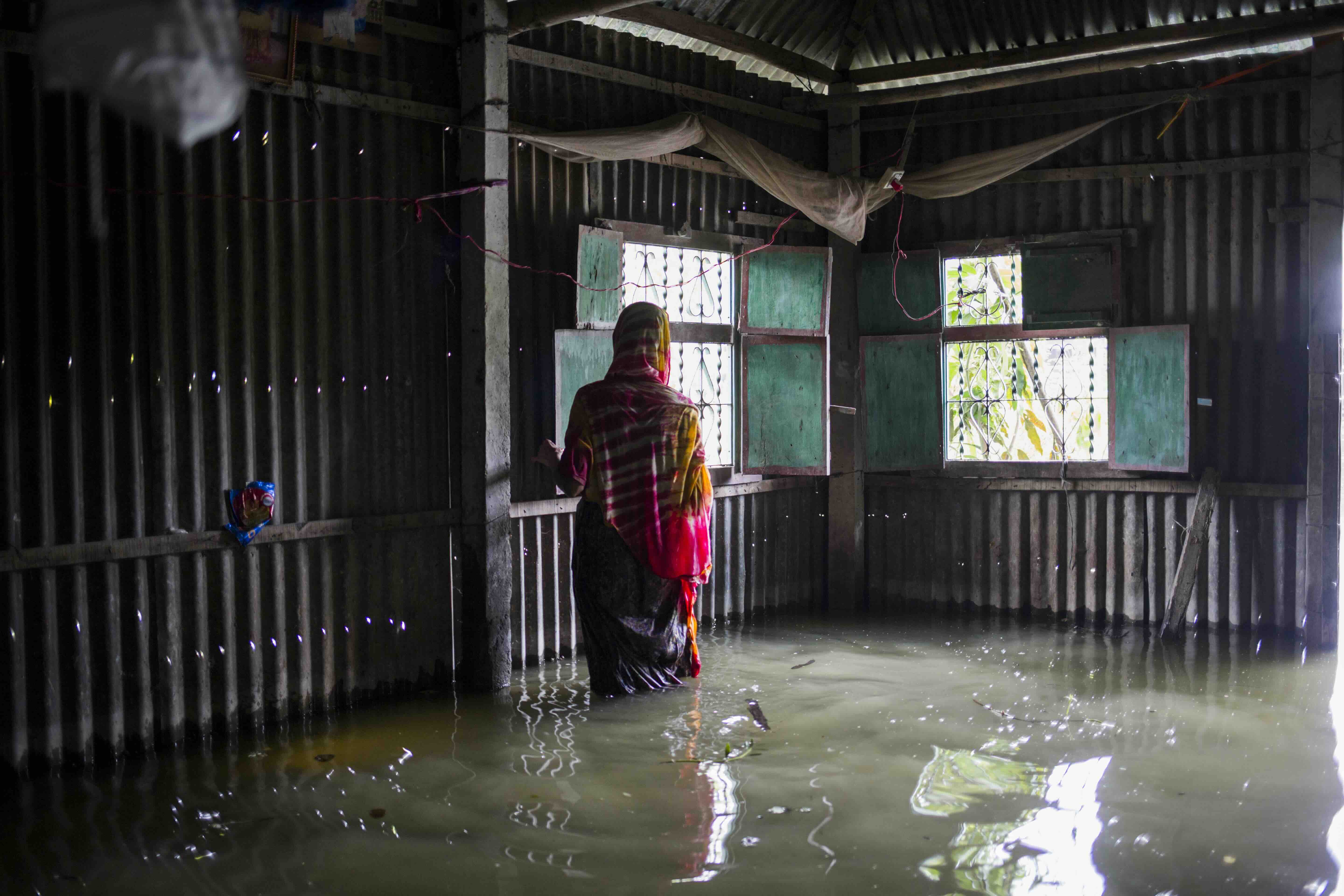 Jorina Begum, de 60 años, revisa su casa dañada por las inundaciones en Sirajganj, Bangladesh, después de que las graves inundaciones de 2020 obligaran a su familia a refugiarse al borde de la carretera durante dos meses.