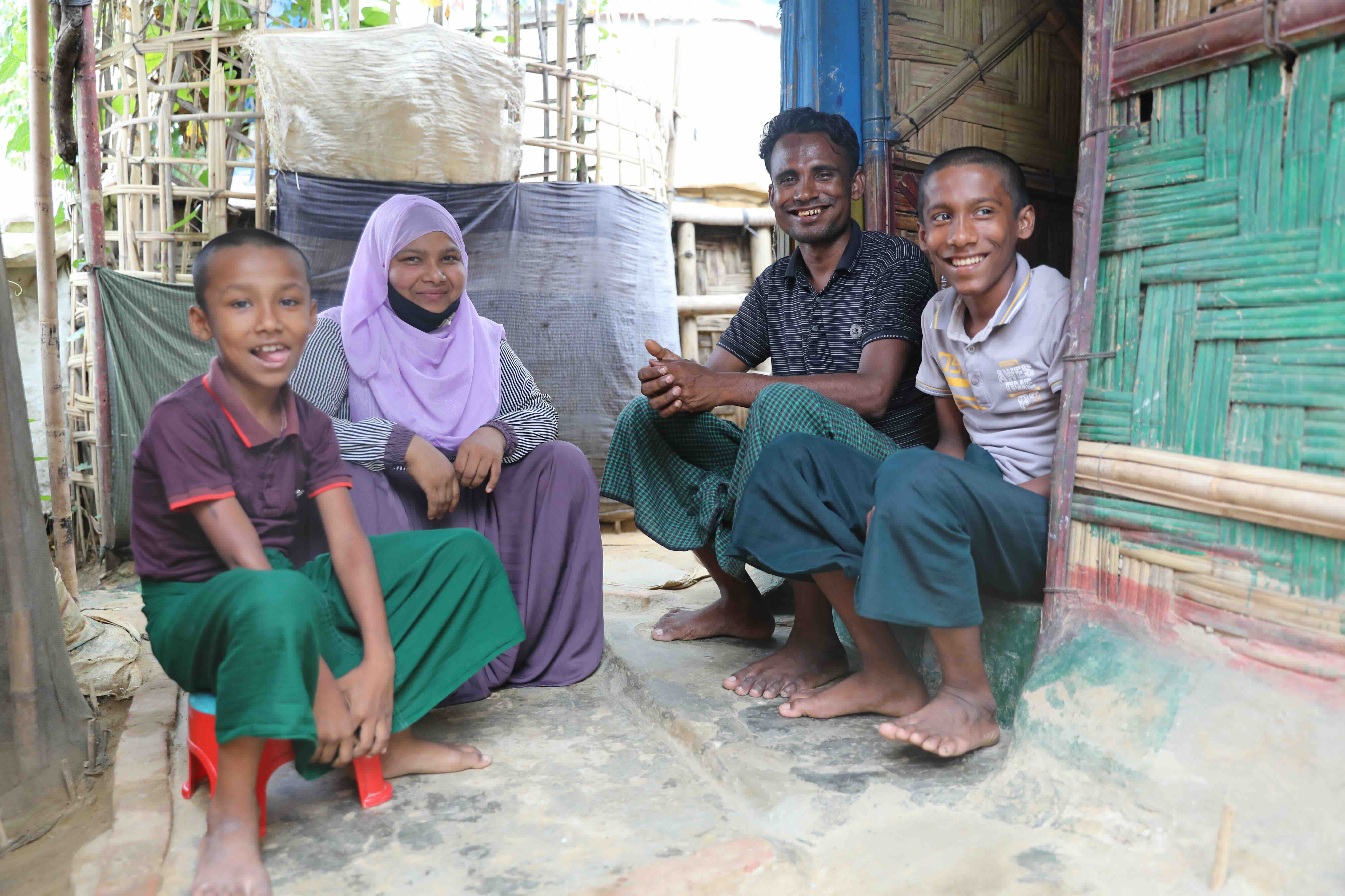 Sayedul Amin (second from right) and Setara Begum (second from left) sit in front of their shelter with their two sons. 