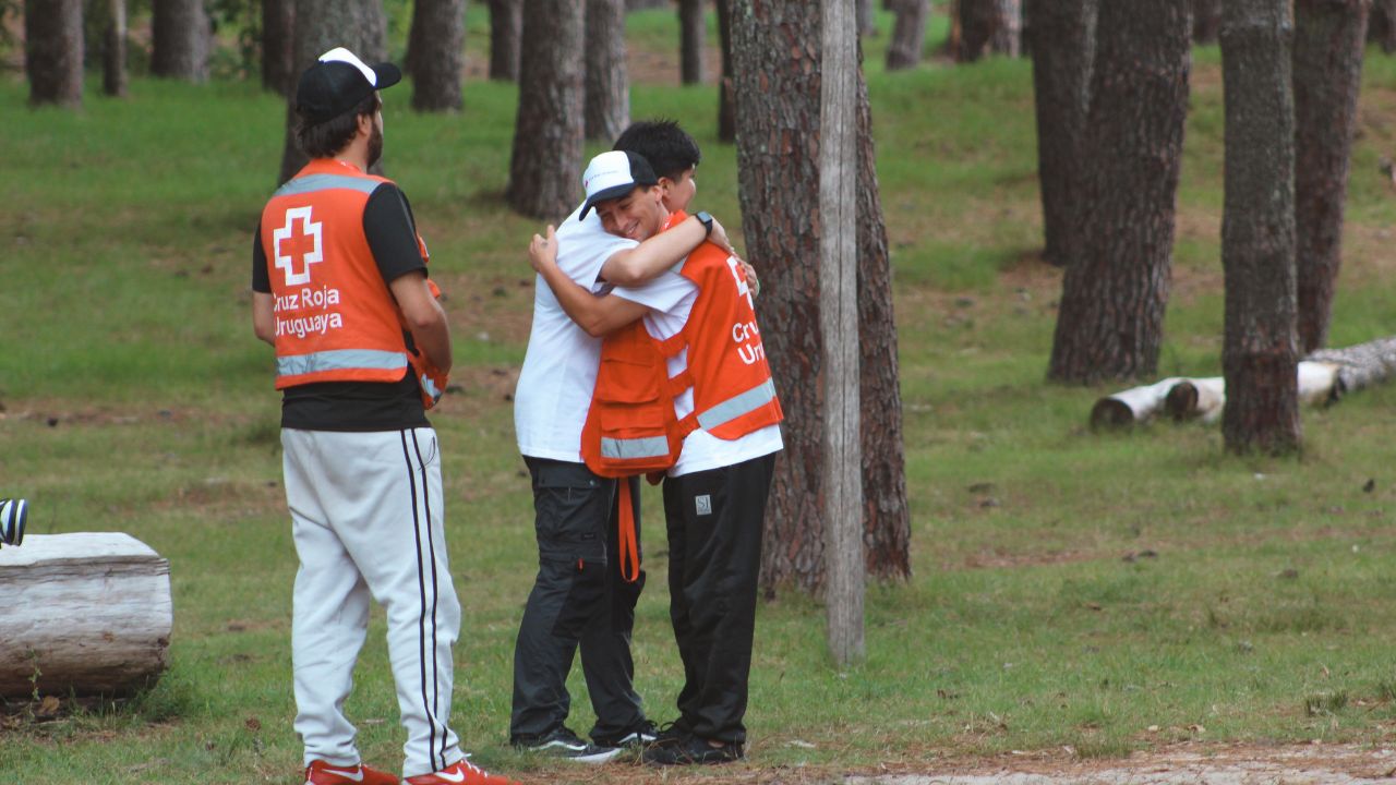 Dos jóvenes voluntarios de la Cruz Roja Uruguaya se abrazan sonrientes en el campamento de juventud realizado en Kiyú, San José, en marzo de 2025. 