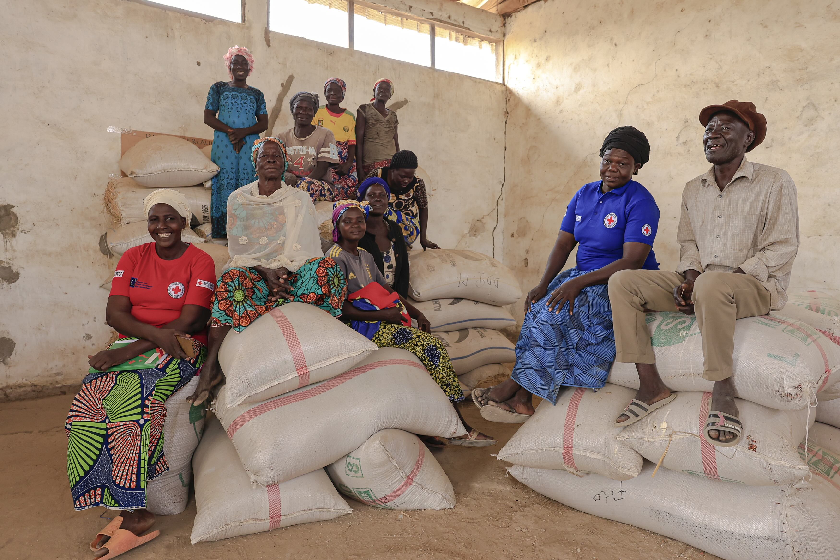 Members of the Soubota Common Initiative Group sit on sacks of grain that they store in their cereal bank to ensure people in the area always have food to eat.