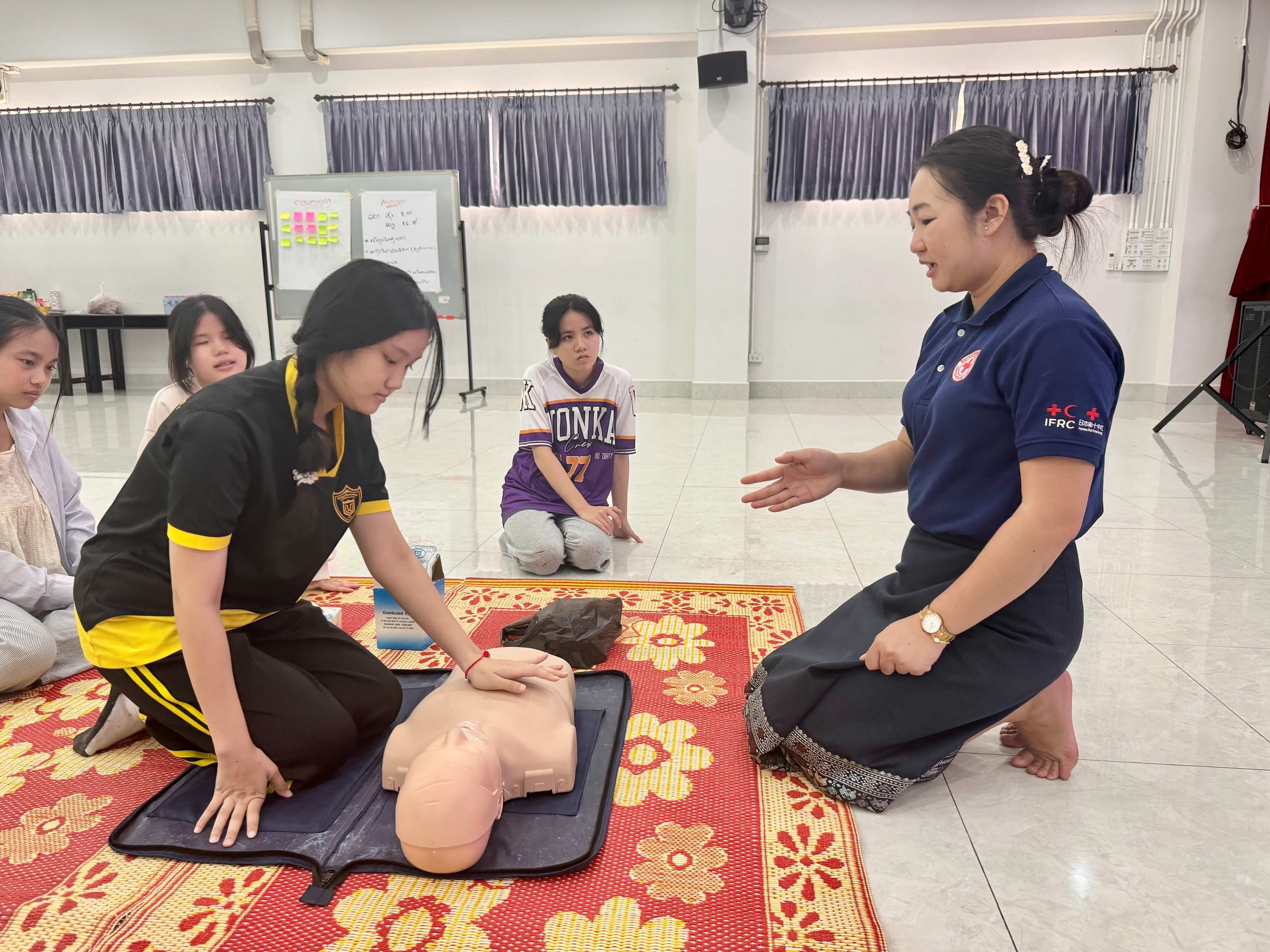 A first aid trainer from the Lao Red Cross shows students how to properly perform cardiopulmonary resuscitation (CPR).