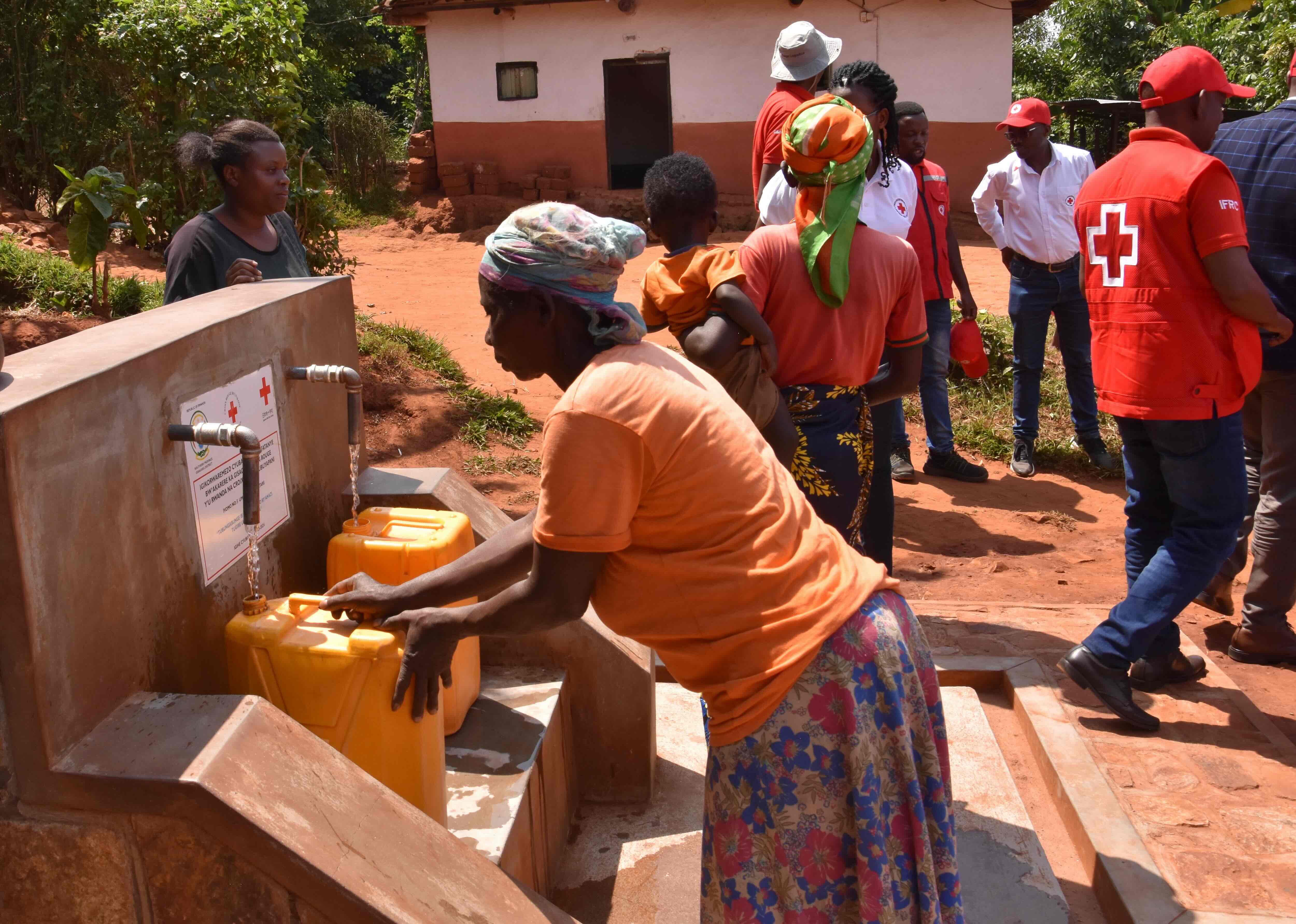 A resident of one of Rwanda's 'Model Villages' fills a jug with water from a tap installed by the Rwanda Red Cross.